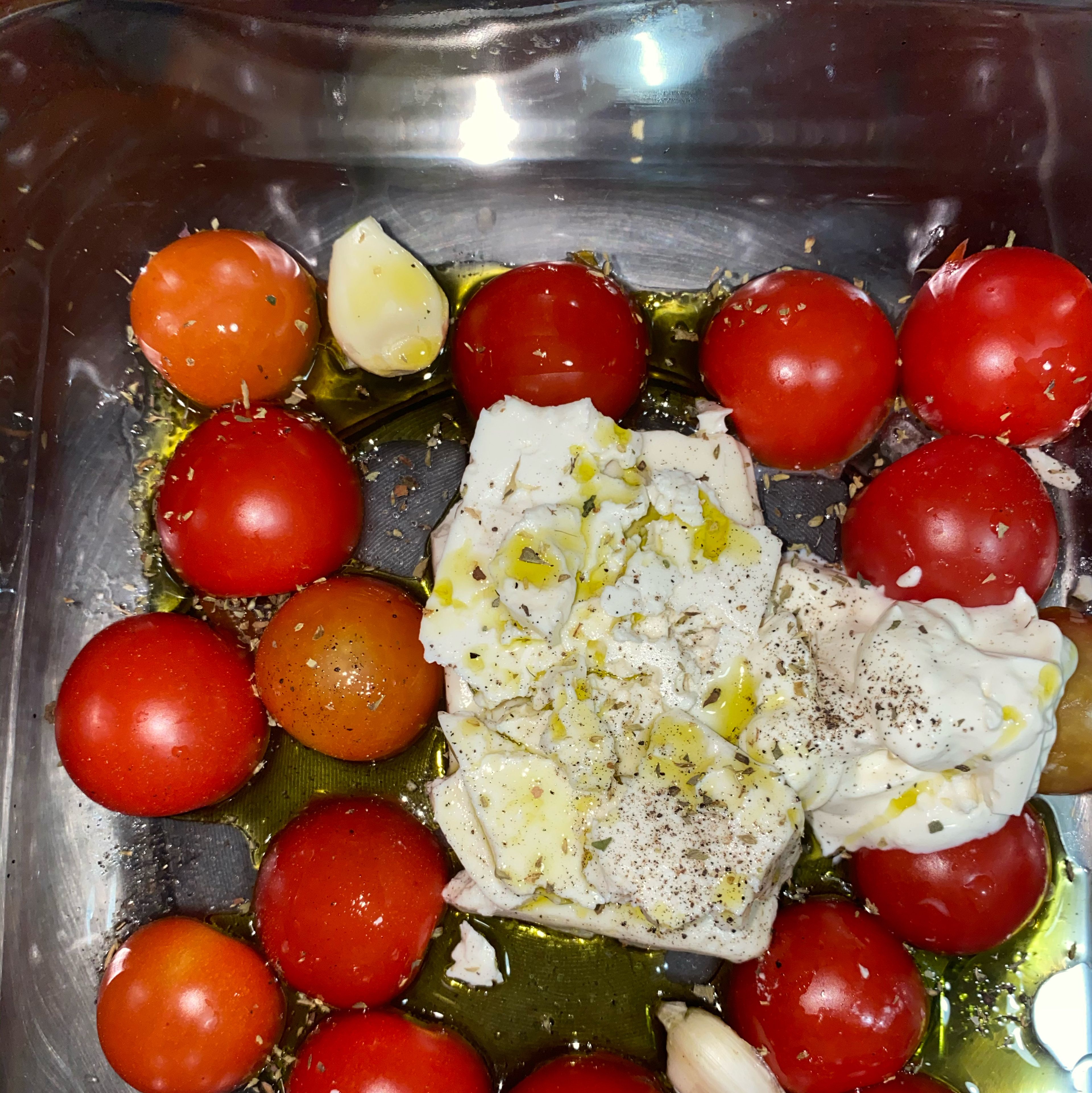 To a pan add sliced in half cherry tomatoes, 2-3 cloves of garlic, a block of Feta Cheese, a tbs of sower cream or cream cheese and some oregano and drizzle the extra virgin olive oil all over it. Add salt if the feta cheese is not salty enough.