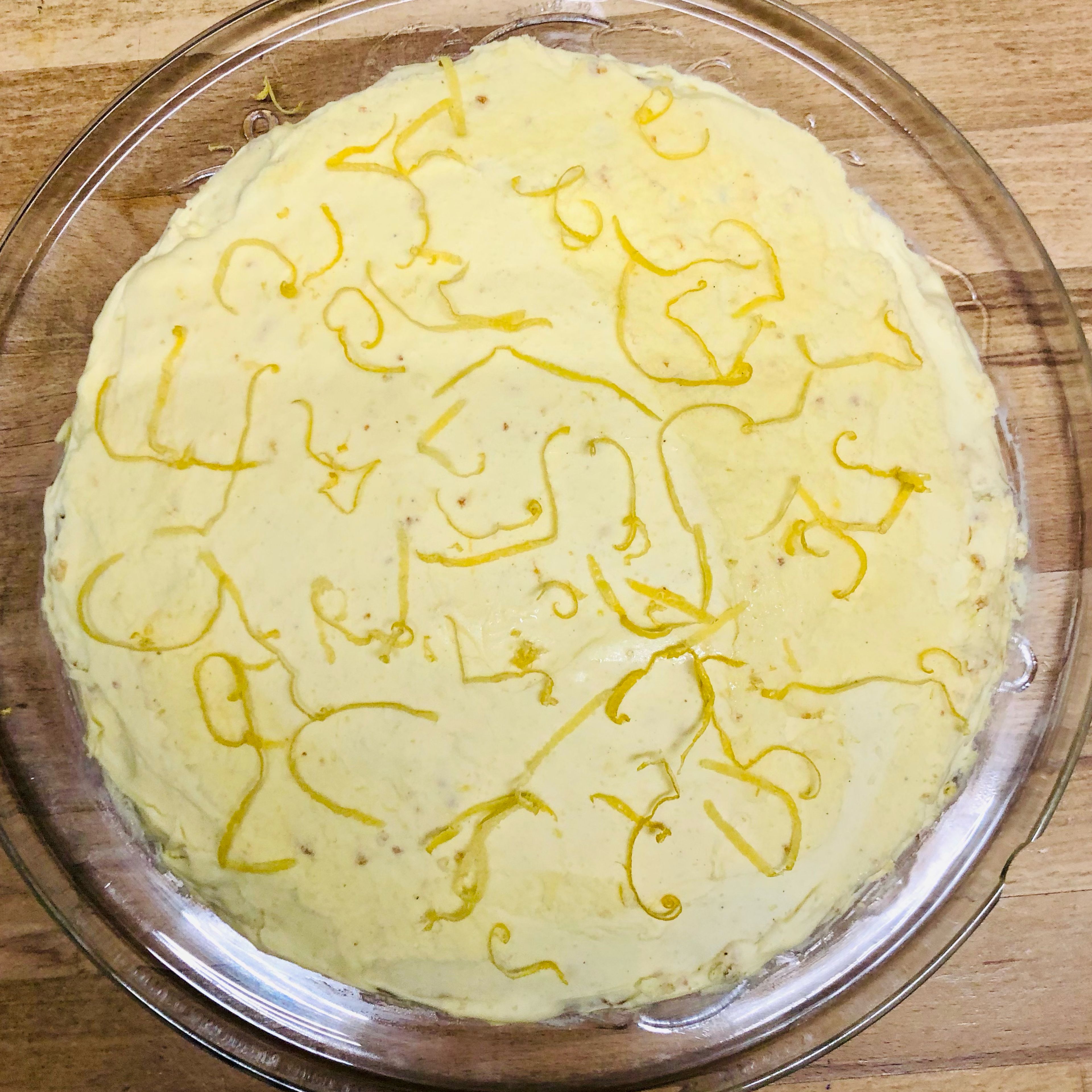 Jetzt wird der Zitronenkuchen einmal durchgeschnitten. Zwischen die Böden wird das Zitronen-Pudding-Frosting gestrichen und auch der Kuchen wird damit eingestrichen. Die Zitronenzesten werden auf die Oberfläche des Kuchens gelegt.
