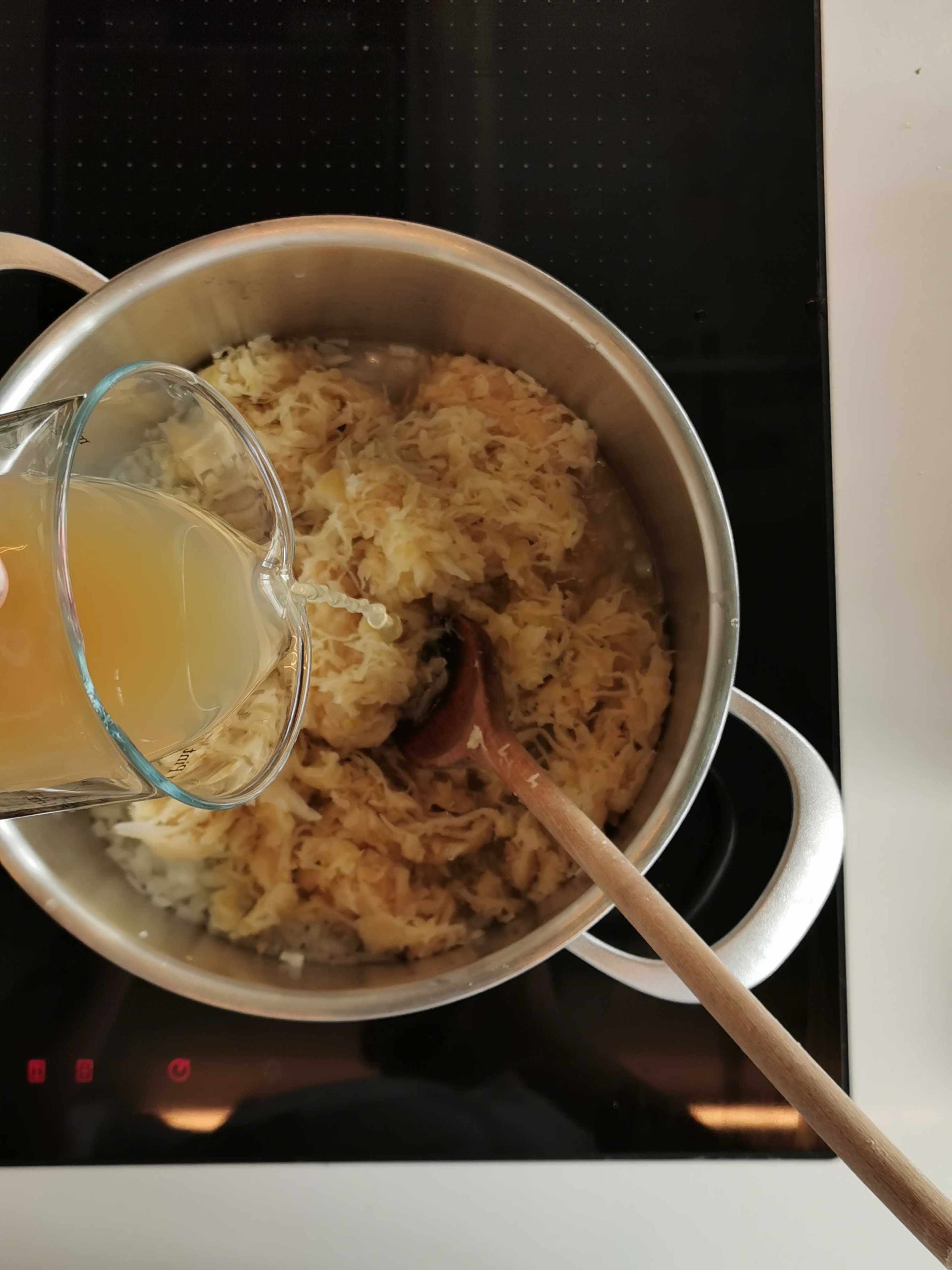 Restliche Zwiebel schälen und fein würfeln. Öl in einem Topf erhitzen, Zwiebel darin glasig dünsten. Sauerkraut und Kümmel zufügen, mit 250 ml der Eisbeinbrühe und Apfelsaft ablöschen. Ca. 30 Minuten garen.