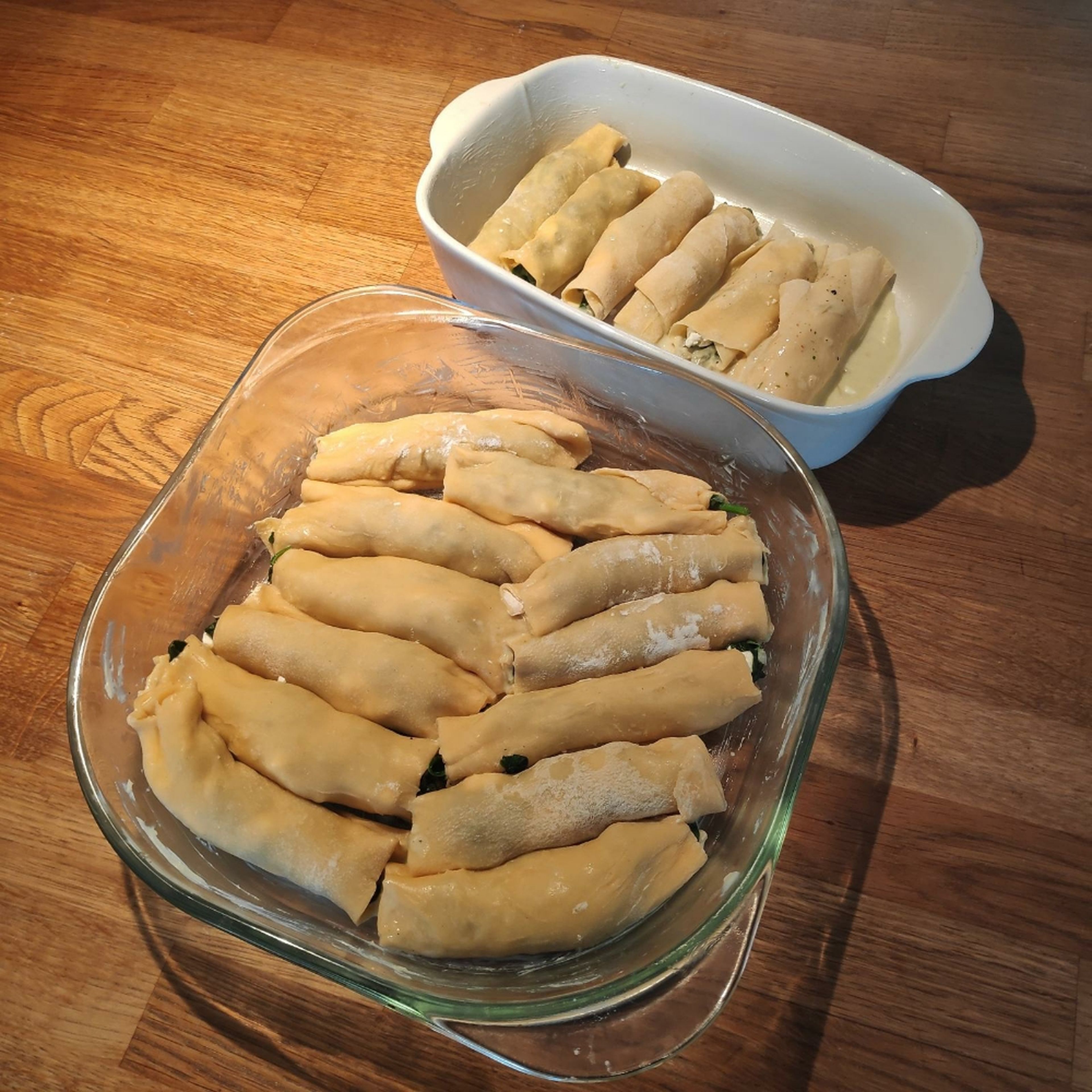 Diesen Schritt mit den verbliebenen Teig-Quadraten wiederholen. Die gerollten Cannelloni auf die Béchamelsauce in die Ofenform geben.
