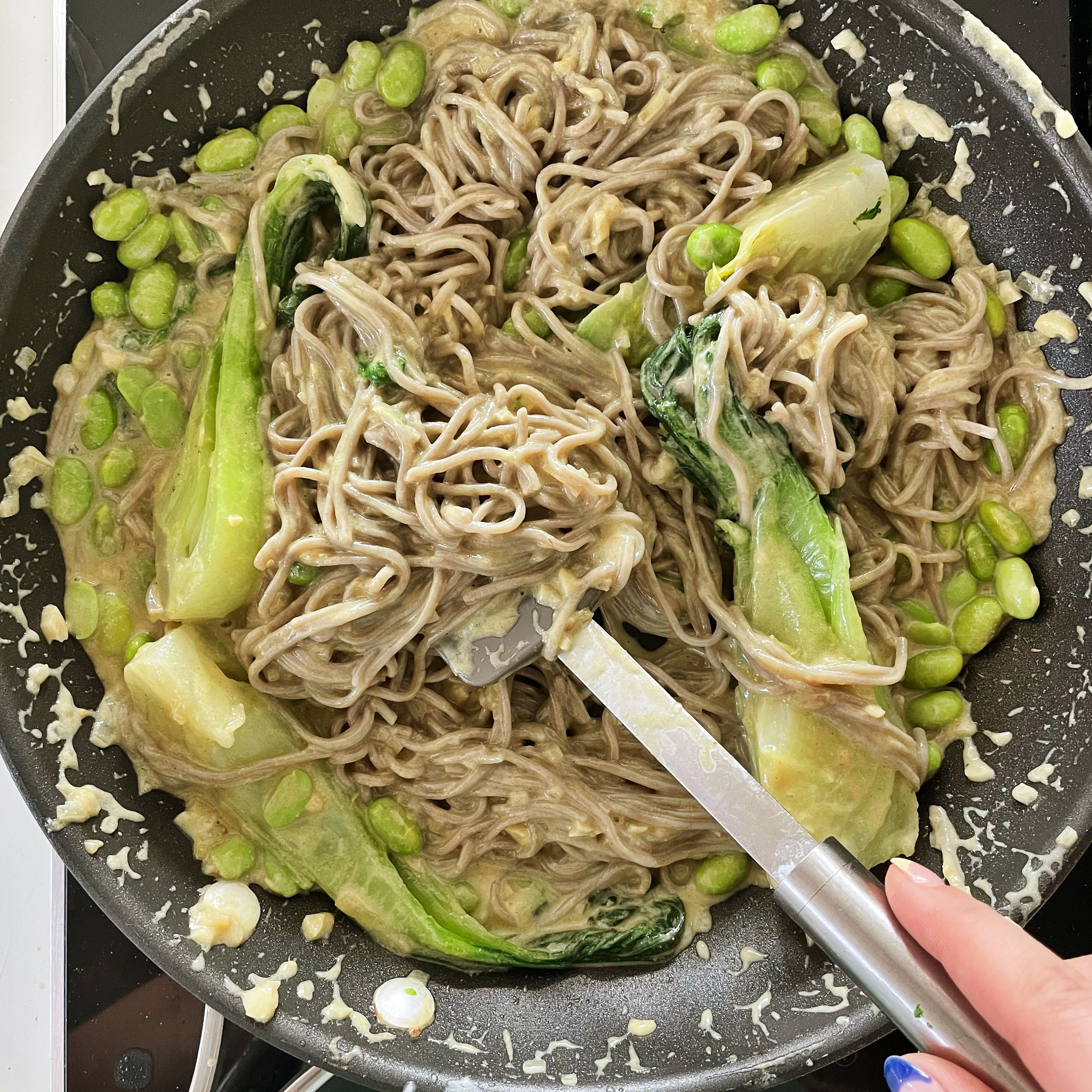 Heat coconut oil in a frying pan. Add the garlic and shallots and sauté. Then add the curry paste, turmeric and salt to sauté as well. Now add the edamame beans and bok choy and fry until the bok choy begins to fall apart. Add the coconut milk and simmer for approx. 5 min. Add the soba noodles and thoroughly mix everything together. Season with pepper and salt and serve immediately. Serve with lime, sesame seeds and chili oil.