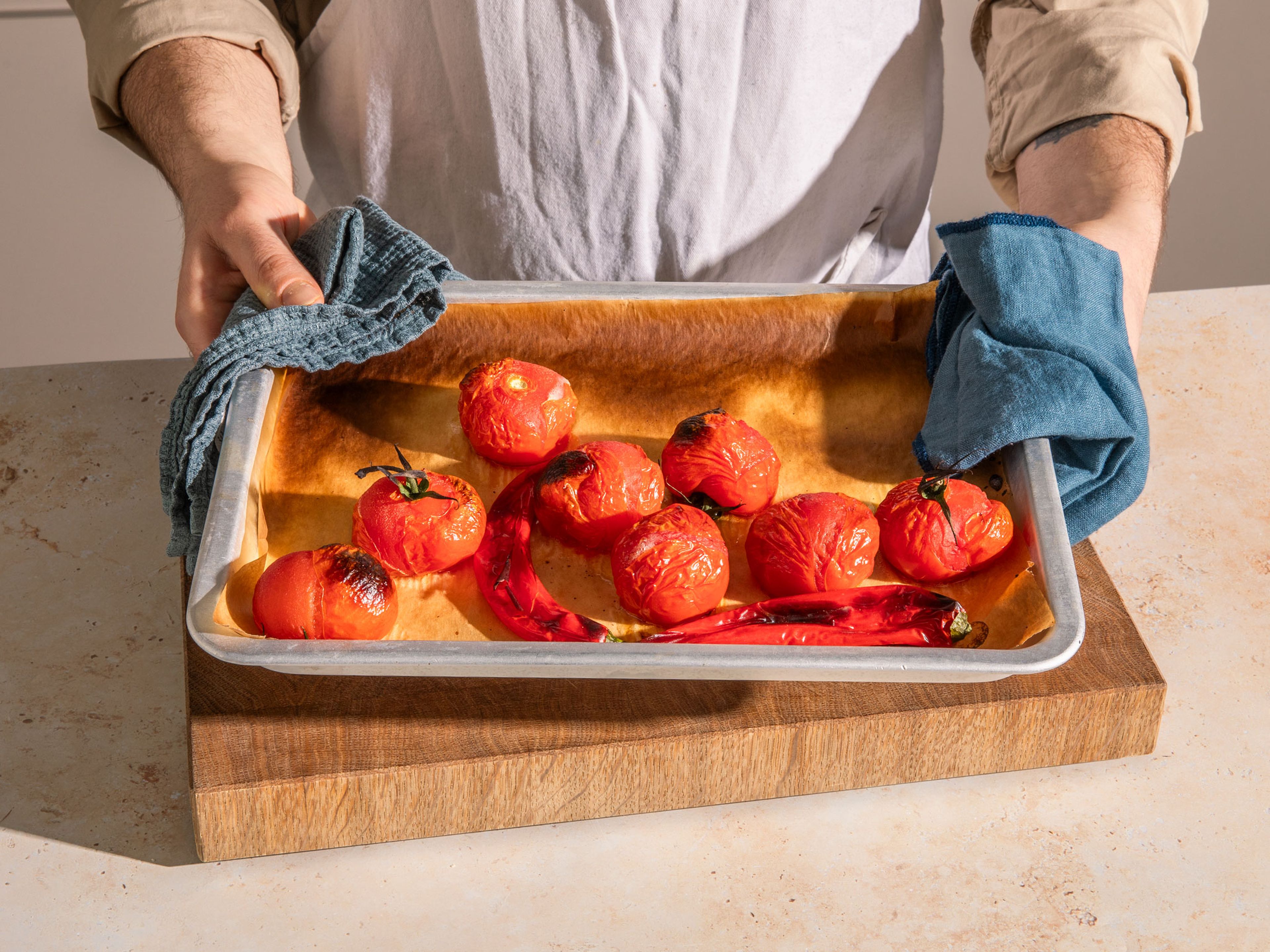 Für den Tomaten-Dip die Grillfunktion des Ofens auf hohe Stufe stellen. Die Tomaten und Chilischoten auf ein mit Backpapier ausgelegtes Backblech legen und unter dem Grill ca. 15 Min. garen oder bis beides angekohlt und weich ist. Beides in eine Schüssel geben, mit Frischhaltefolie oder einem Teller abdecken und ca. 20 Min. dämpfen lassen. Nach dem Dämpfen beides schälen.