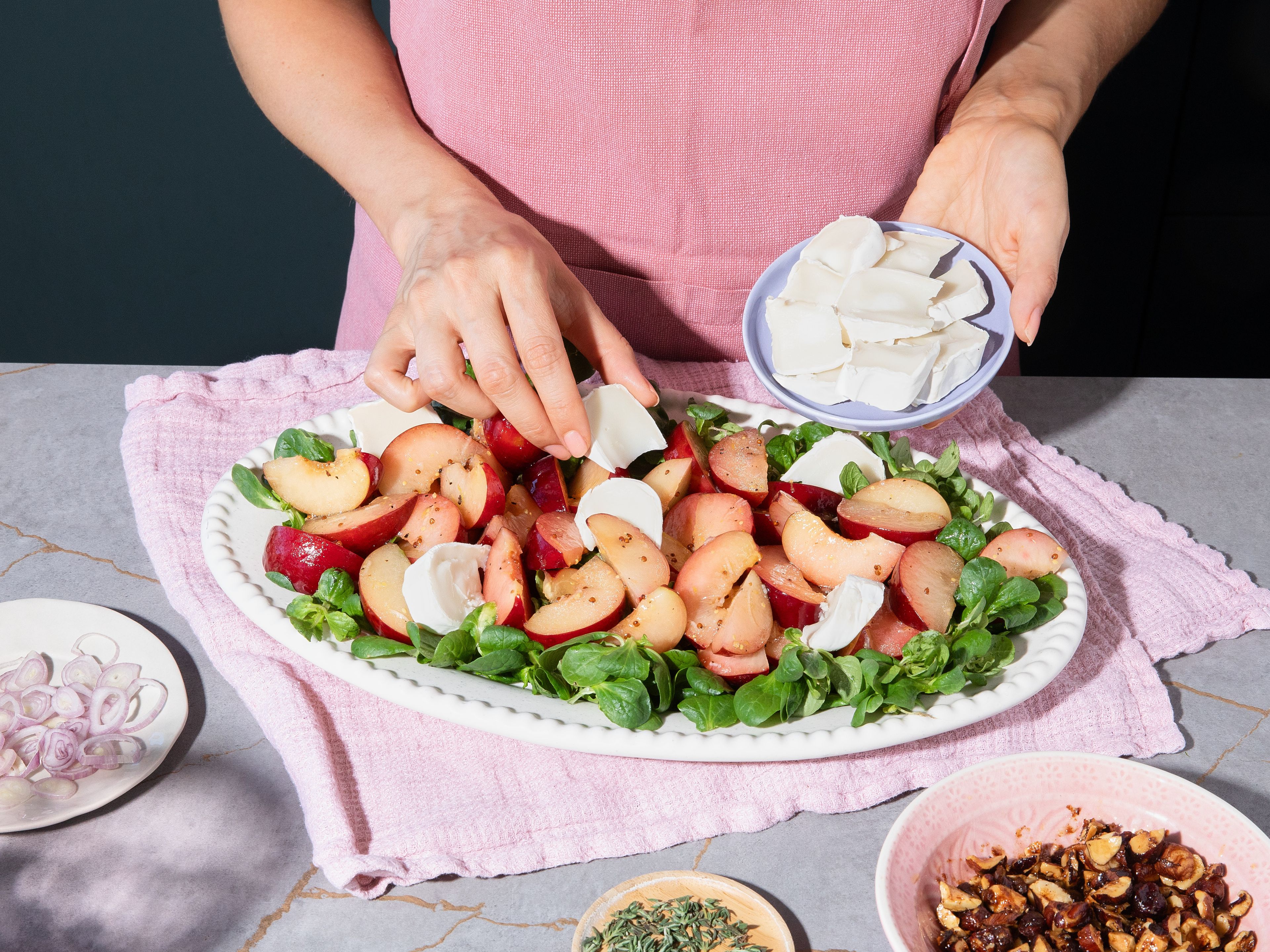 Arrange lamb's lettuce on plates or large serving platter. Distribute marinated plums and shallots with dressing on top. Slice goat cheese roll or tear into rough pieces and place on top with seasoned hazelnuts. Sprinkle with fresh thyme and serve.