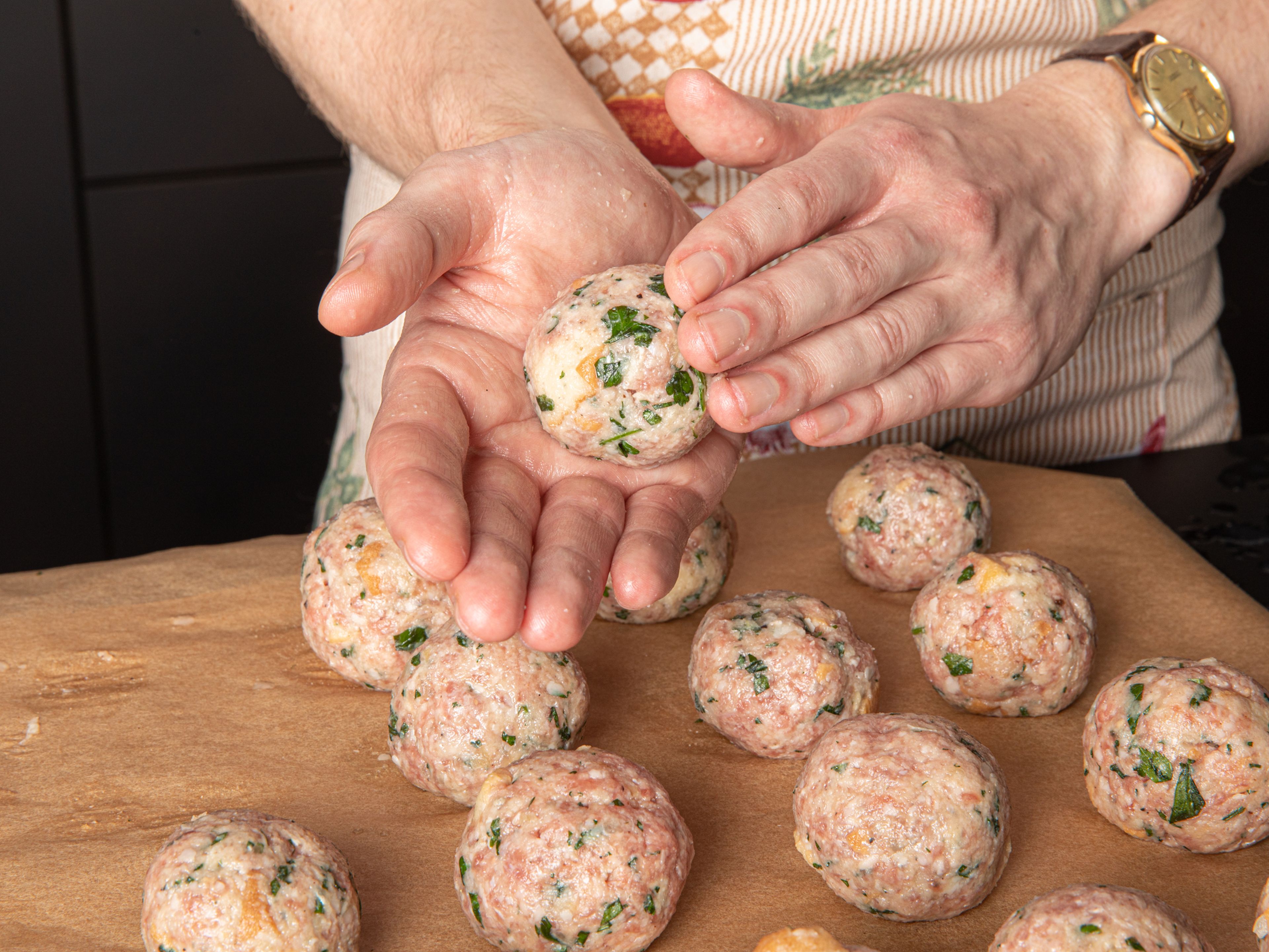 In the meantime, fill a bowl with water and line a baking sheet or cutting board with baking paper. Form approx. 20 meatballs the size of table tennis balls, by gently rotating the mixture between wet hands, then place on the baking paper.