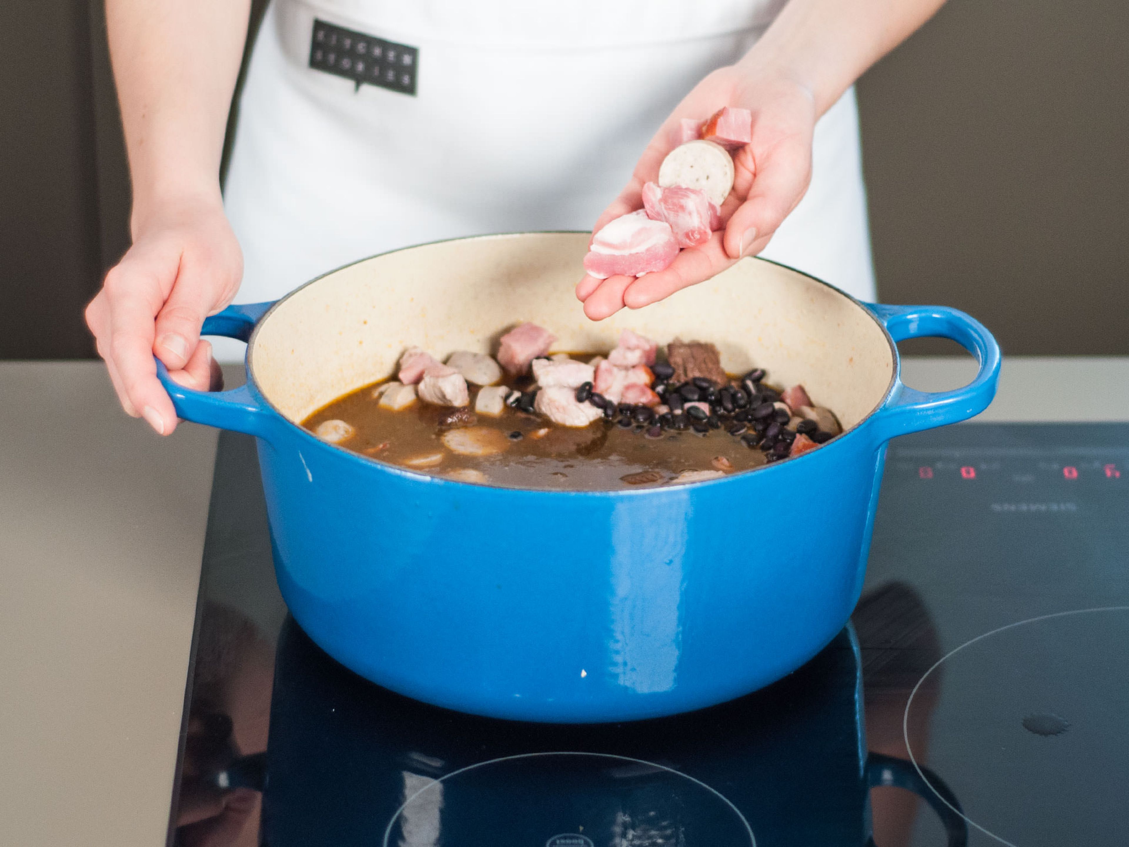 Add black beans, smoked pork chop, pork belly, and sausages. Continue to simmer over medium-low heat for approx. 45 – 60 min. until beans are cooked through and the sauce has slightly thickened.