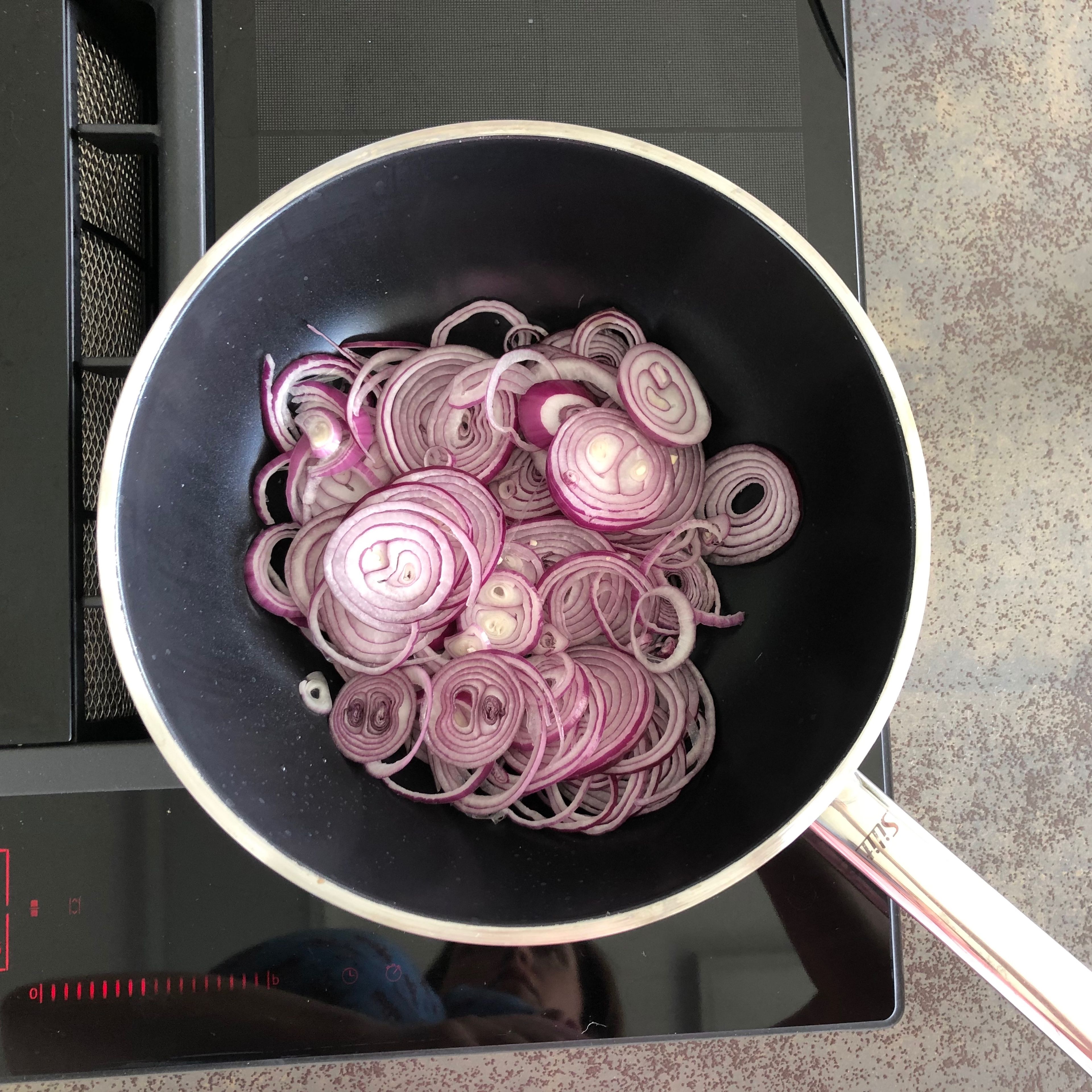 To make the onion, bacon, and chickpea topping, first slice the some of the onions, heat olive oil in a frying pan and sauté slowly over low heat, until very soft.