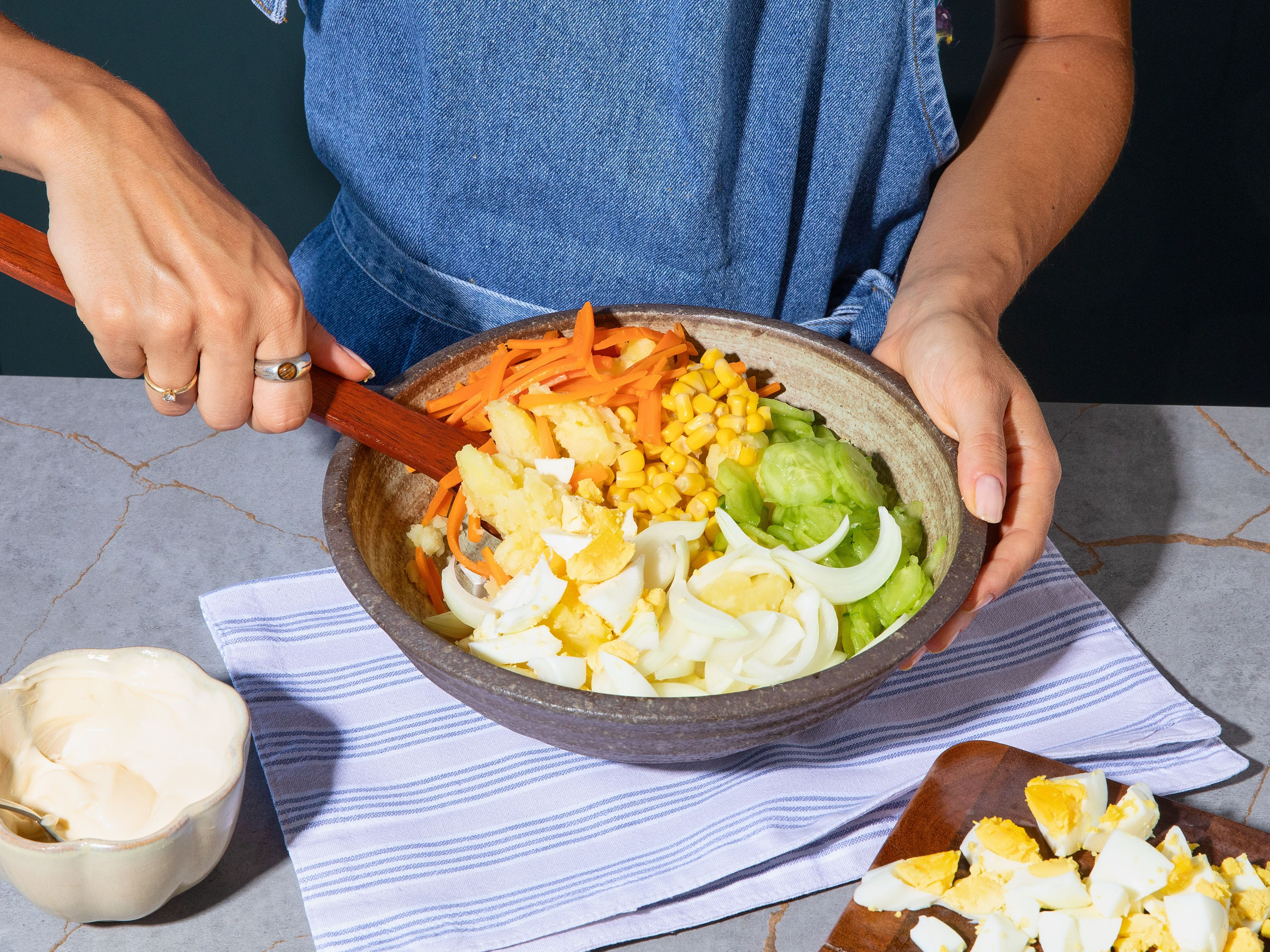 Once eggs are cooked, rinse under cold water, peel and roughly chop. Add eggs, carrots, cucumber and onion to the cooled potatoes. Fold in mayonnaise and season with salt and pepper. Top with crispy fried onions and spring onions.
