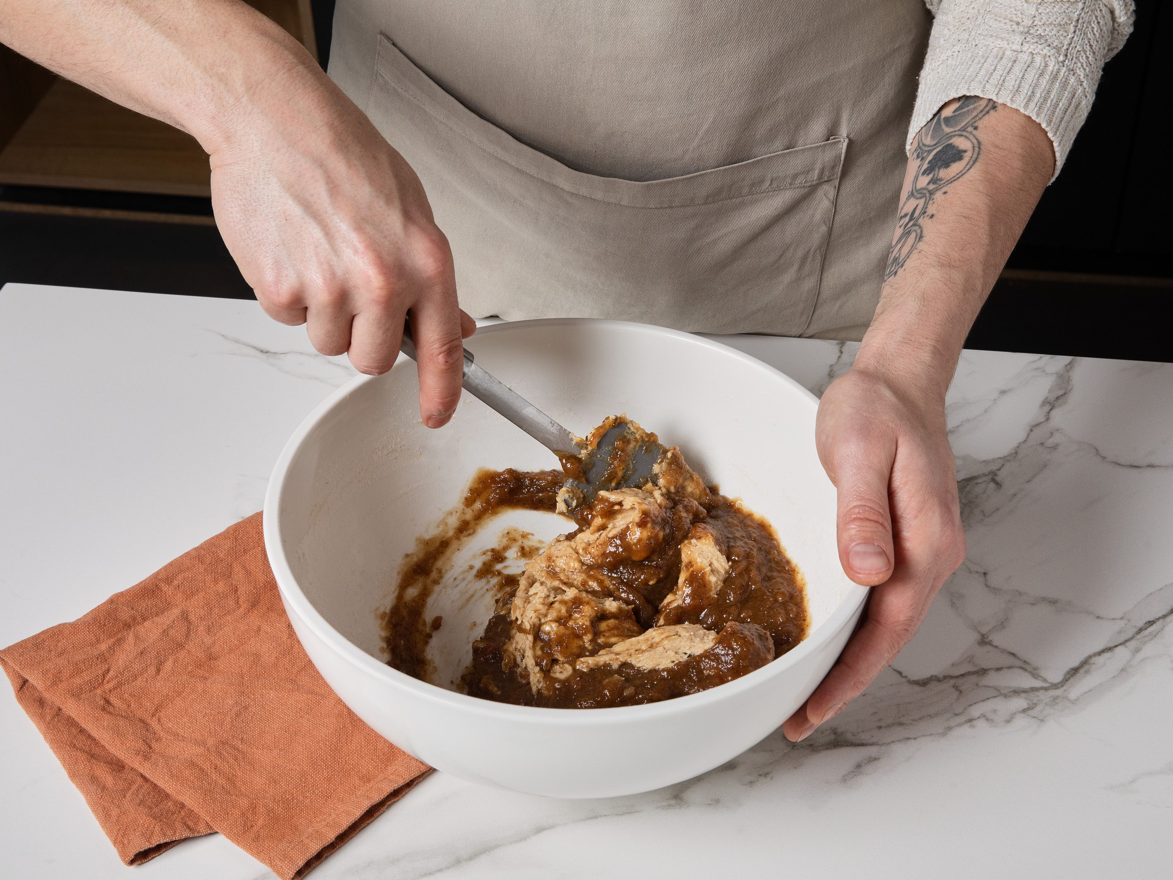 Die eingeweichten Datteln mit einem Pürierstab oder einer Gabel zu einer stückigen Masse verarbeiten. Für den Teig weiche Butter und braunen Zucker schaumig schlagen. Eier zugeben und gut einarbeiten. Mehl, Zimt, Kardamom und Backpulver vermengen und unterrühren, bis ein glatter Teig entsteht. Zum Schluss die zerkleinerten Datteln unterheben, bis sie gleichmäßig verteilt sind.