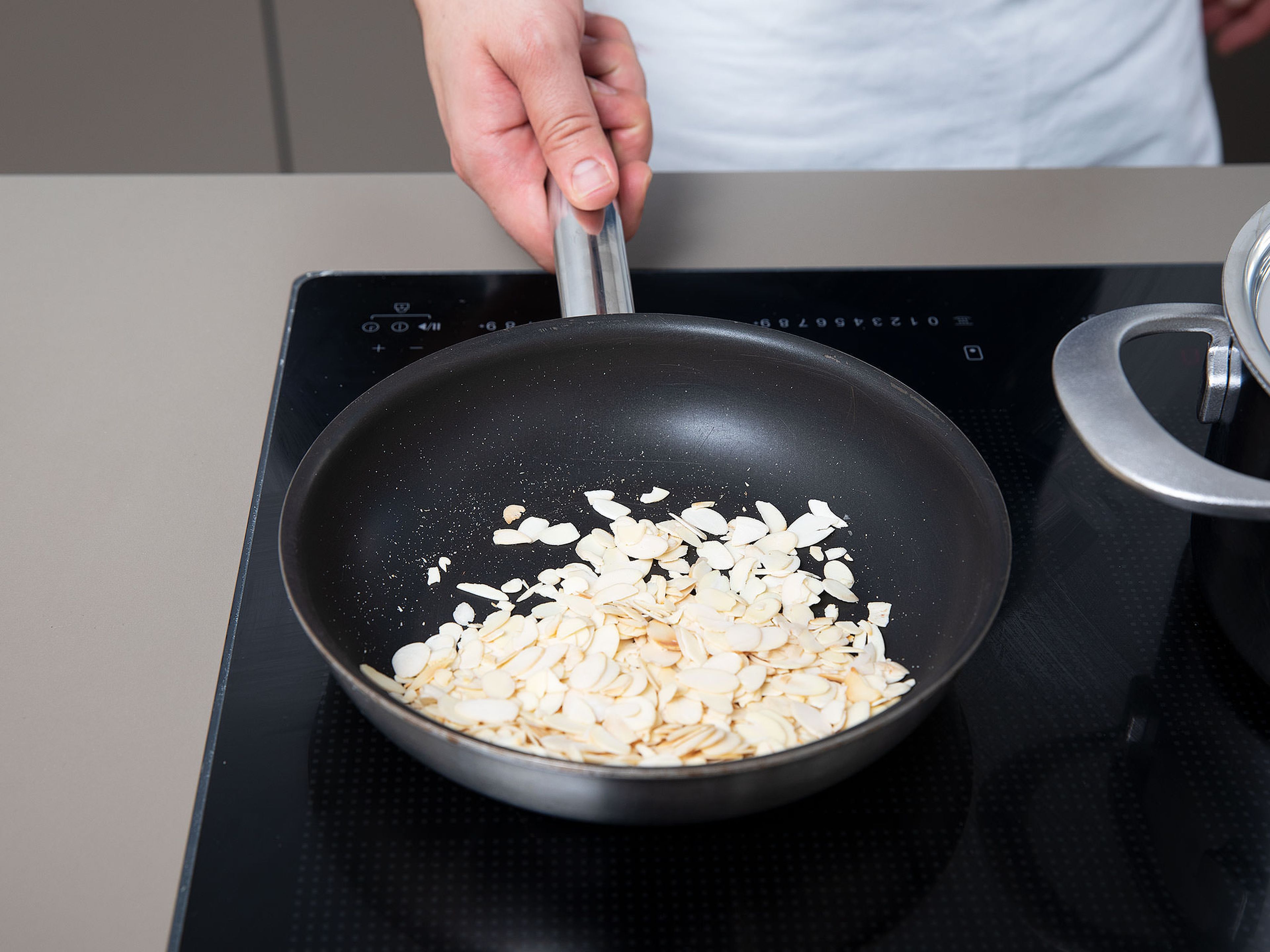 In a frying pan, toast sliced almonds over medium heat until golden.
