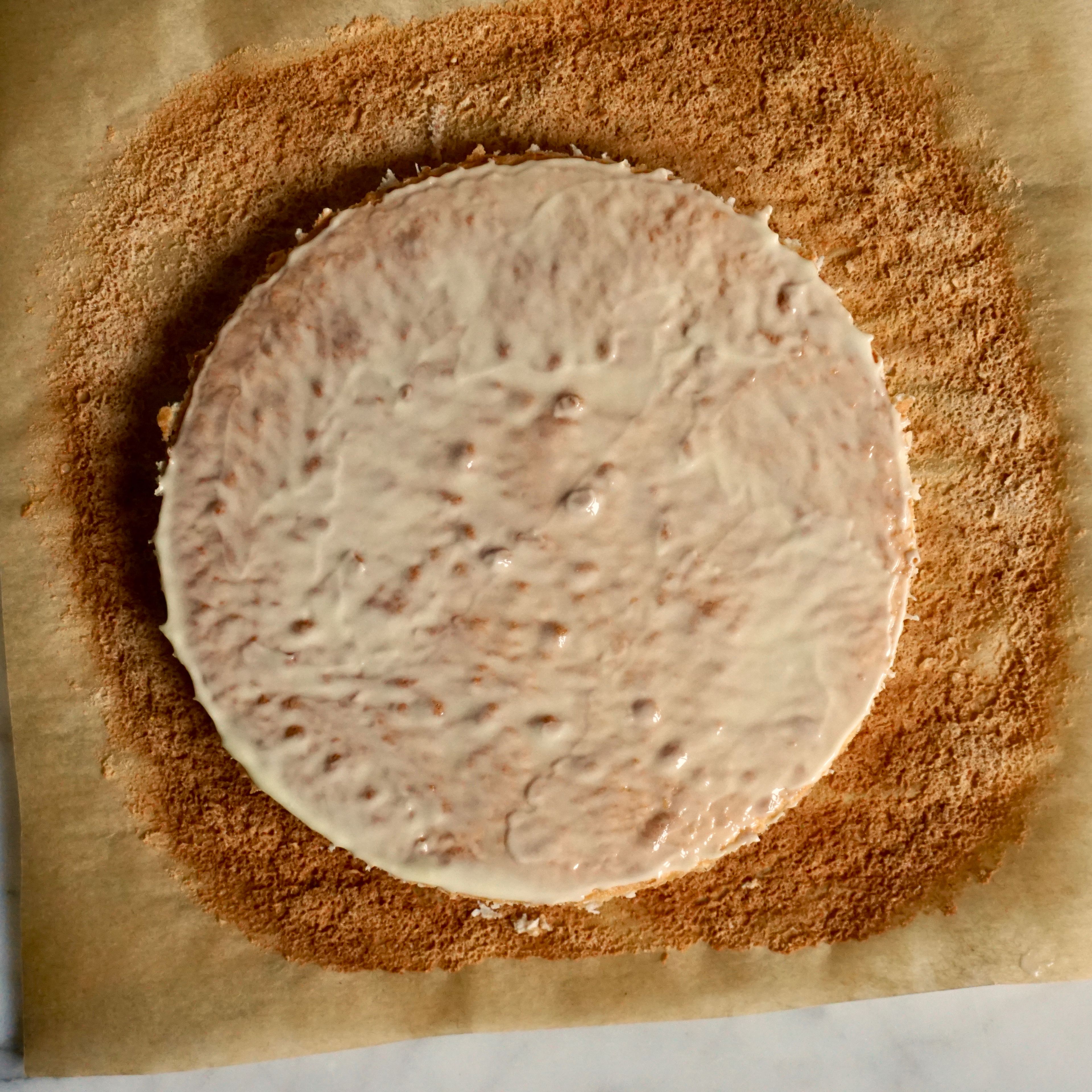 Eiweiß in einer Schüssel mit 30g Zucker und einer Prise Salz aufschlagen. Gemahlene Mandeln unterheben und die Masse auf einem Bogen Backpapier geben und zu einem Kreis mit ca. 14cm Durchmesser verstreichen. Dacquoise für ca. 10 Minuten backen. 20g weiße Schokolade schmelzen und den Mandeldaquoise damit bepinseln.