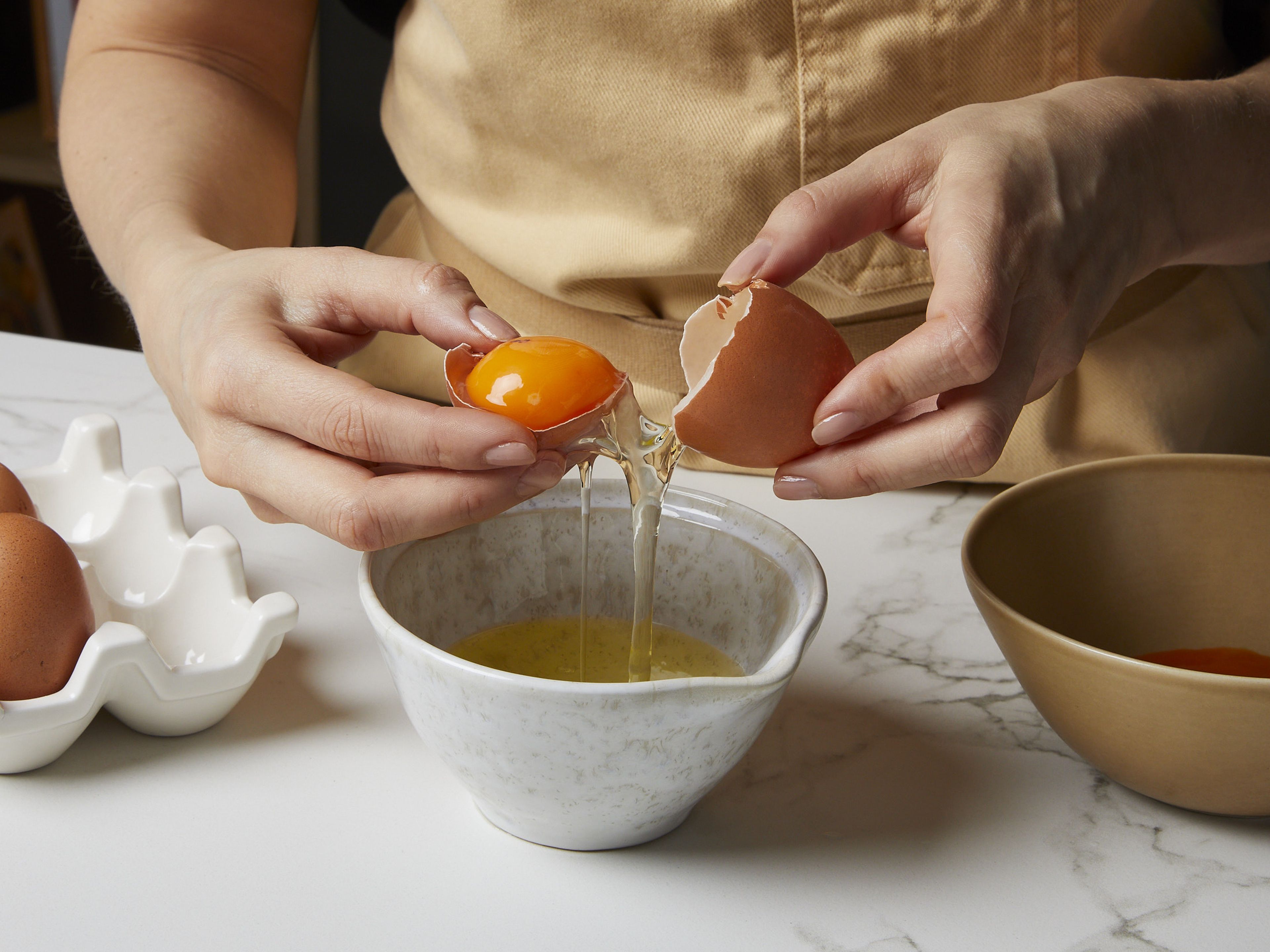 Für unser Sauce Hollandaise Rezept das Eigelb vom Eiweiß trennen und das Eigelb in eine kleine Schüssel geben. Das Eiweiß kannst du für eine andere Verwendung aufheben. Die Butter in einem Topf schmelzen, dabei darauf achten, dass sie nicht braun wird. Eigelb, Zitronensaft, Salz und Pfeffer in einem hohen Gefäß wie einem Messbecher verrühren.