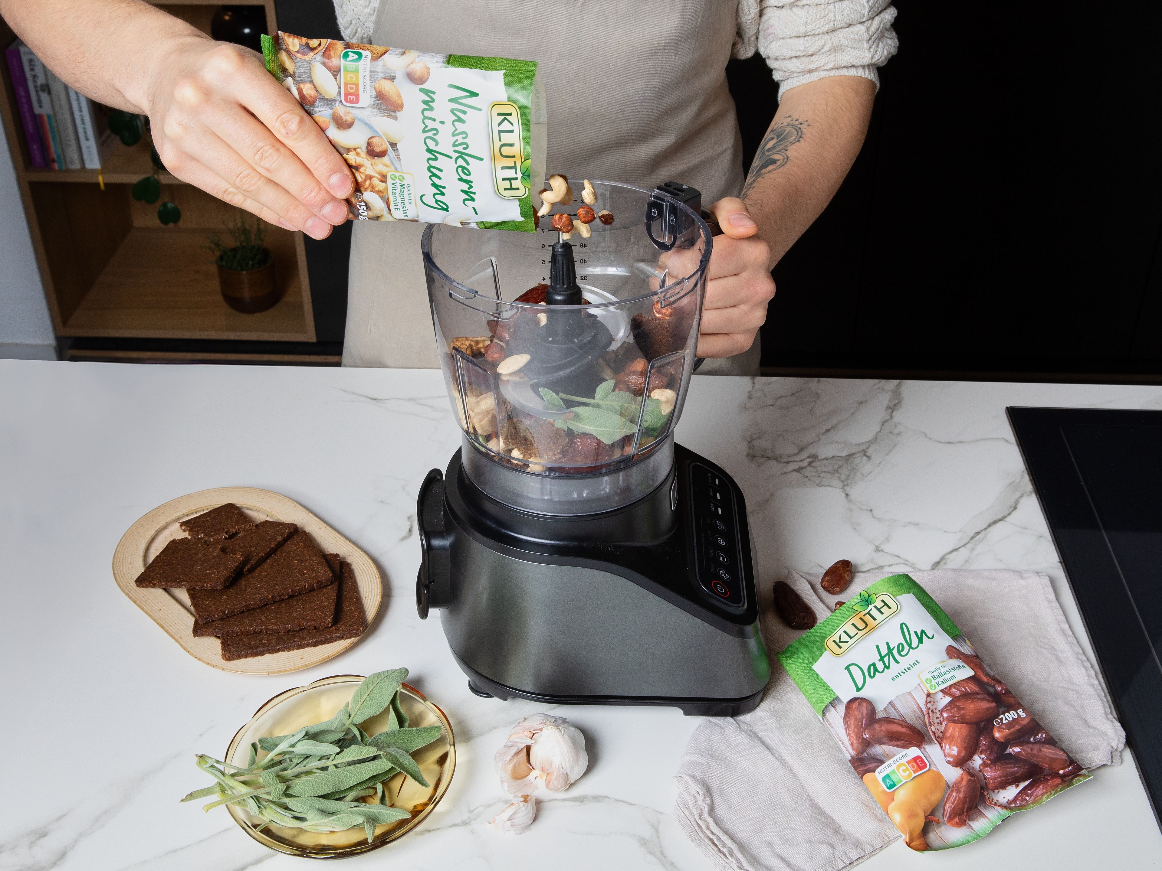 Den Backofen auf 180 °C (Ober-/Unterhitze) vorheizen. Datteln, Nusskernmischung, Salbei, Knoblauch und Pumpernickel in einem Zerkleinerer grob mixen, bis eine stückige, klebrige Füllung entsteht. Falls sie zu trocken ist, etwas Wasser hinzugeben. Mit Salz und Pfeffer abschmecken und beiseitestellen. Rote Zwiebel schälen, halbieren und in feine Halbmonde schneiden. Kartoffeln schälen und in kleine Würfel schneiden. Hokkaido halbieren, entkernen und in ca. 2 cm dicke Spalten schneiden. Grünkohl von den harten Stielen befreien und grob zupfen.