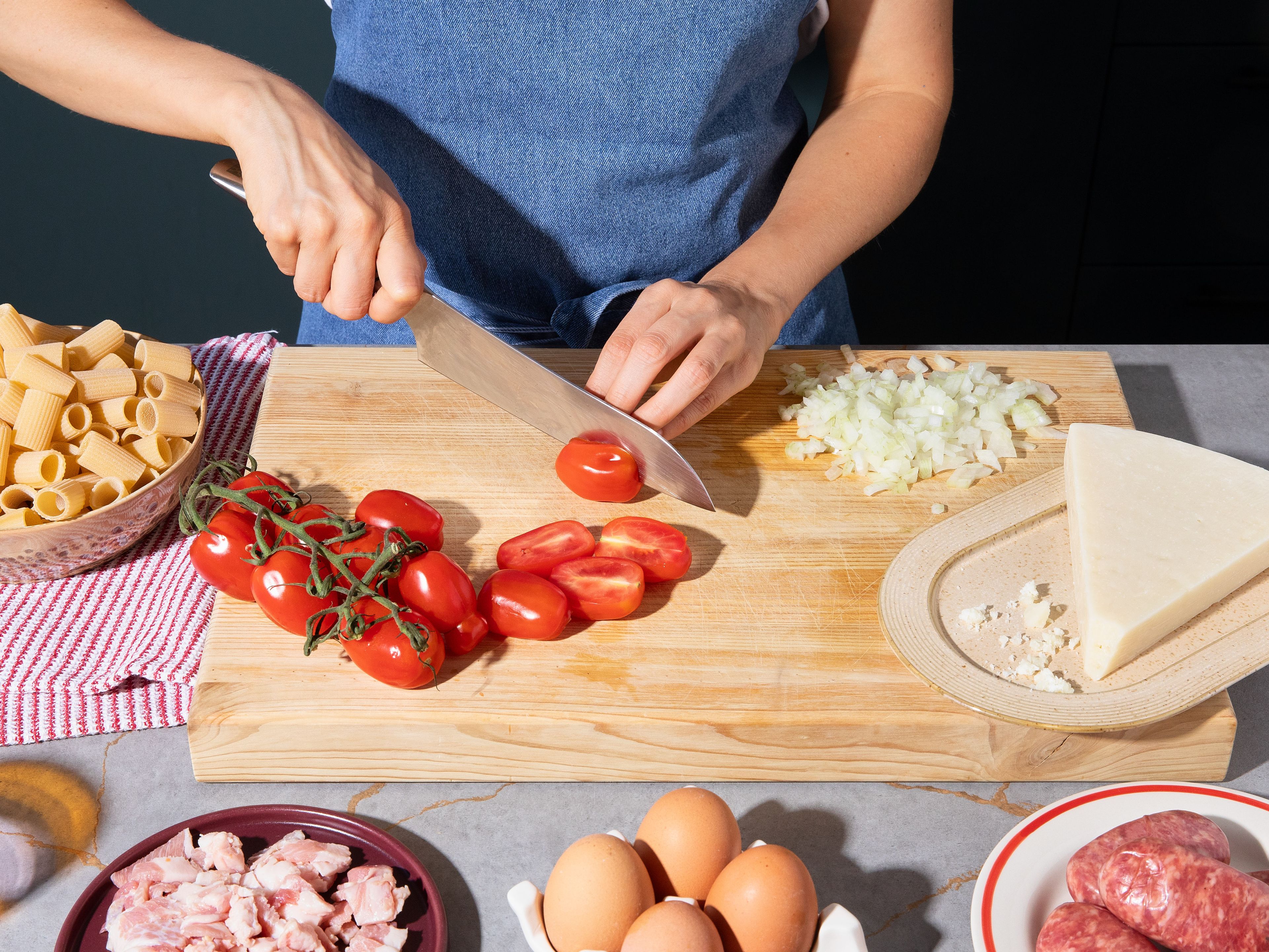 Bring large pot of salted water to boil. Dice onion finely, halve cherry tomatoes. Cut guanciale into small cubes if necessary. Remove salsiccia from casing and tear coarsely. Grate pecorino finely and whisk majority with egg yolk and plenty of black pepper in a bowl.