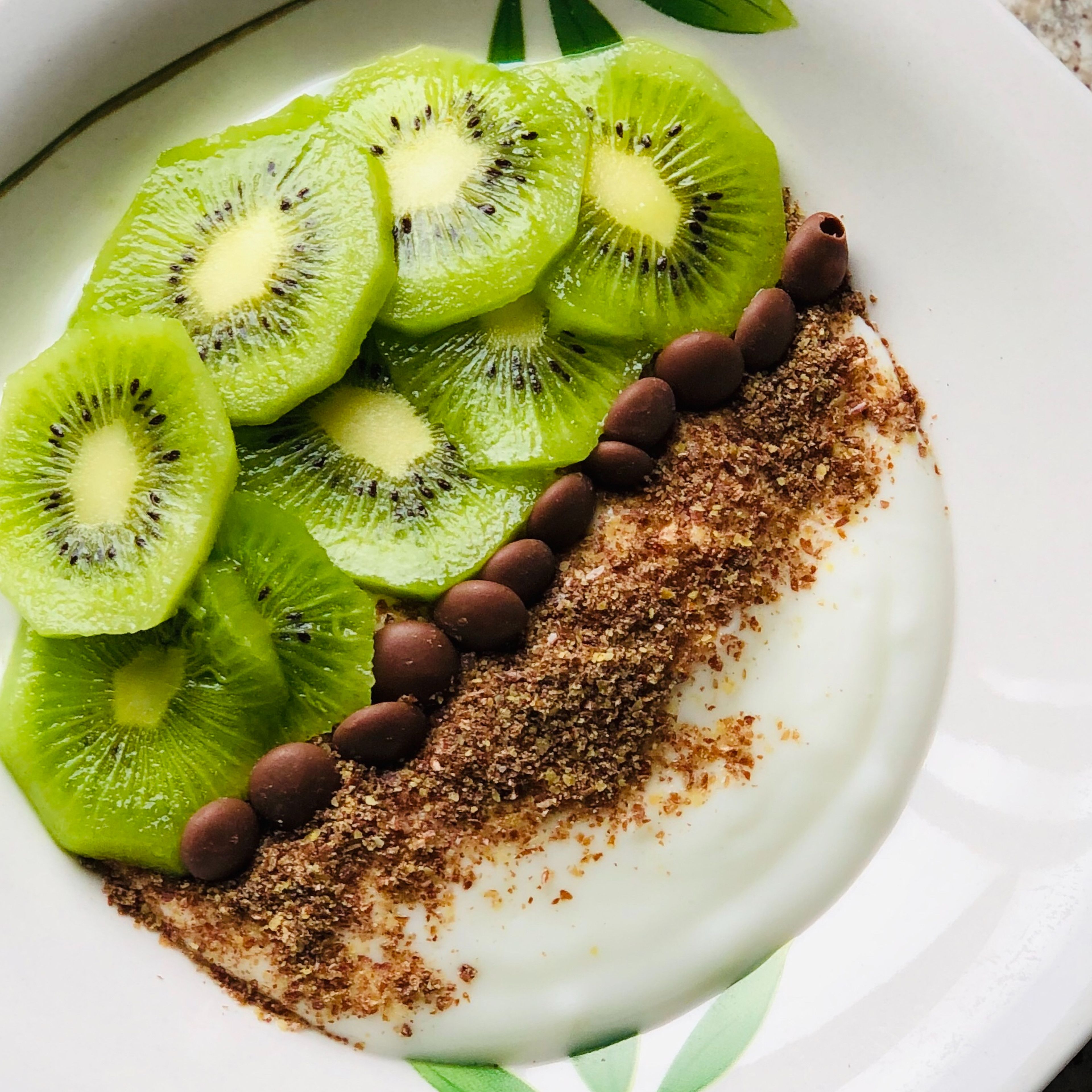 Put the yogurt in a bowl. Now peel the kiwi and cut it into slices. Distribute it on top of the yogurt on the side. Add the flax seeds. Place the chocolate chips and it's ready.