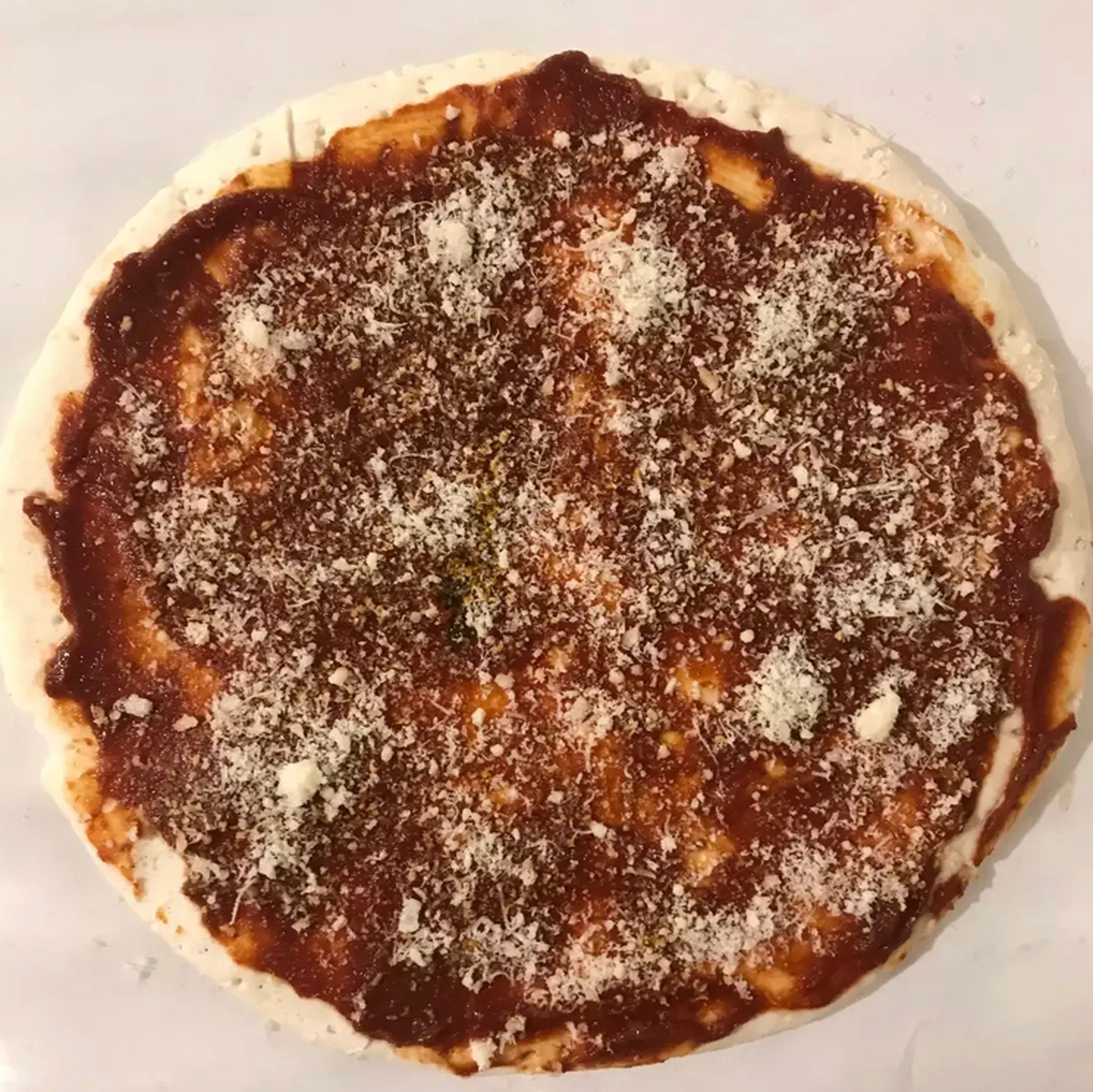 First, preheat the oven to 180 degrees Celsius. If we use homemade dough, it is better to semi-cook it first or put the pizza in the oven for 20 minutes first so that the dough cooks faster. Spread the marinara sauce on the dough and sprinkle with Parmesan cheese powder.