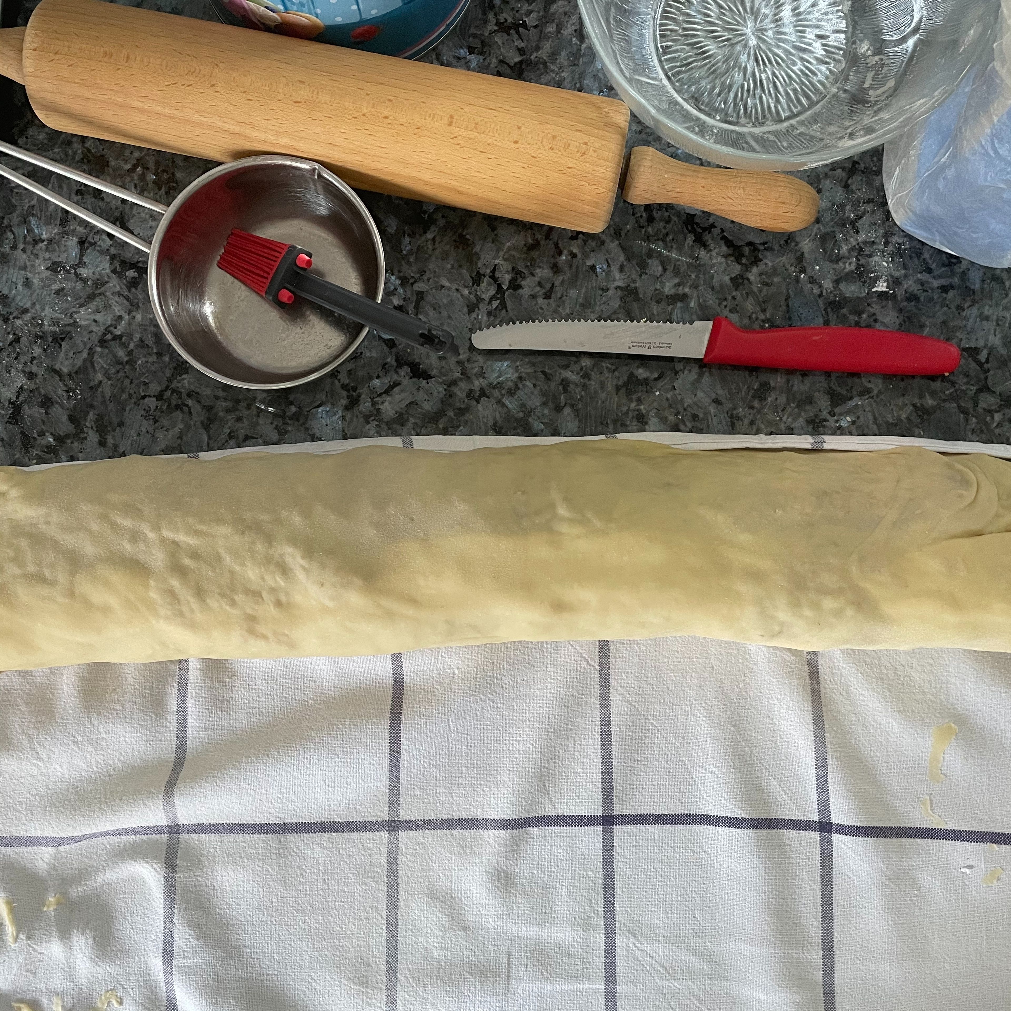 Nun den Strudel vorsichtig, mithilfe des Geschirrtuchs einrollen und auf ein mit Backpapier ausgelegtes Backblech heben. 