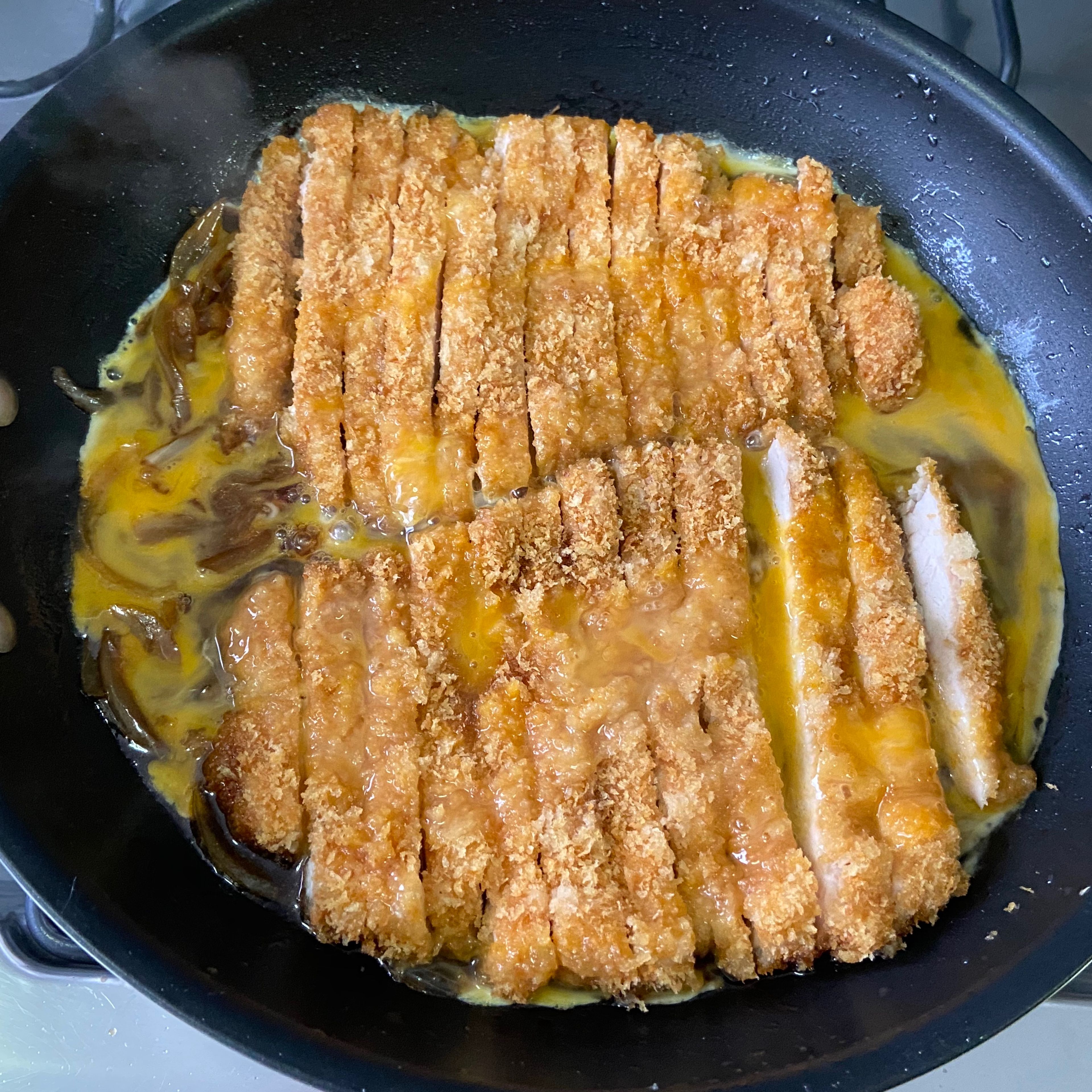 Carefully transfer each sliced cutlet to the pan and then immediately add the egg. Cover with a large lid and cook on medium heat until the egg is set, about 3-5 mins. 