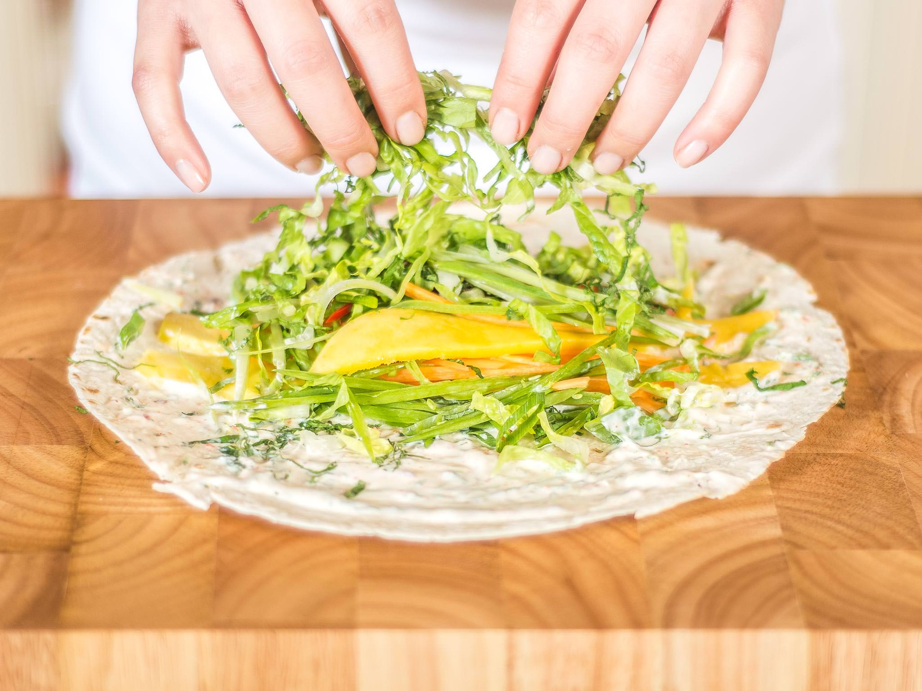 Spread the mixture onto the wraps. Top with sliced vegetables, parsley, and mango.