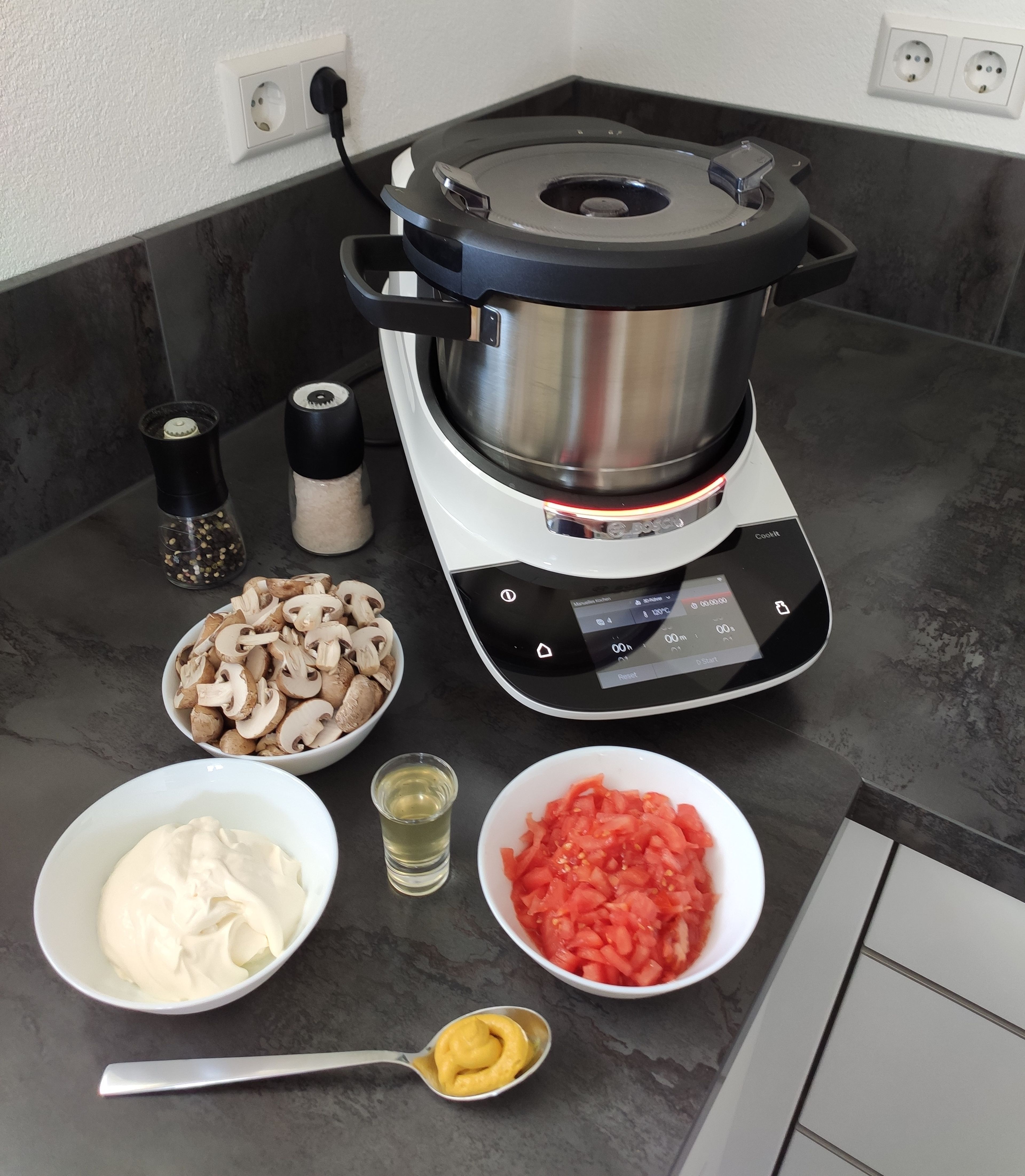 Nun die Tomaten häuten. Dafür die Tomaten an der Unterseite kreuzweise einritzen, in einer Schüssel mit kochenden Wasser übergießen und anschließend mit kalten Wasser abschrecken. Jetzt kann die Haut der Tomate abgezogen werden. Danach die gehäuteten Tomaten klein hacken und mit Crème fraîche, Pilzen, Senf, Wasser der Gewürzgurken, Paprikapulver, Salz und Pfeffer in den Cookit geben und 8 Minuten bei 95 Grad mit dem Cookit 3D-Rührer anbraten (3D-Rührer | Stufe 4 | 95 Grad | 8 Min.).