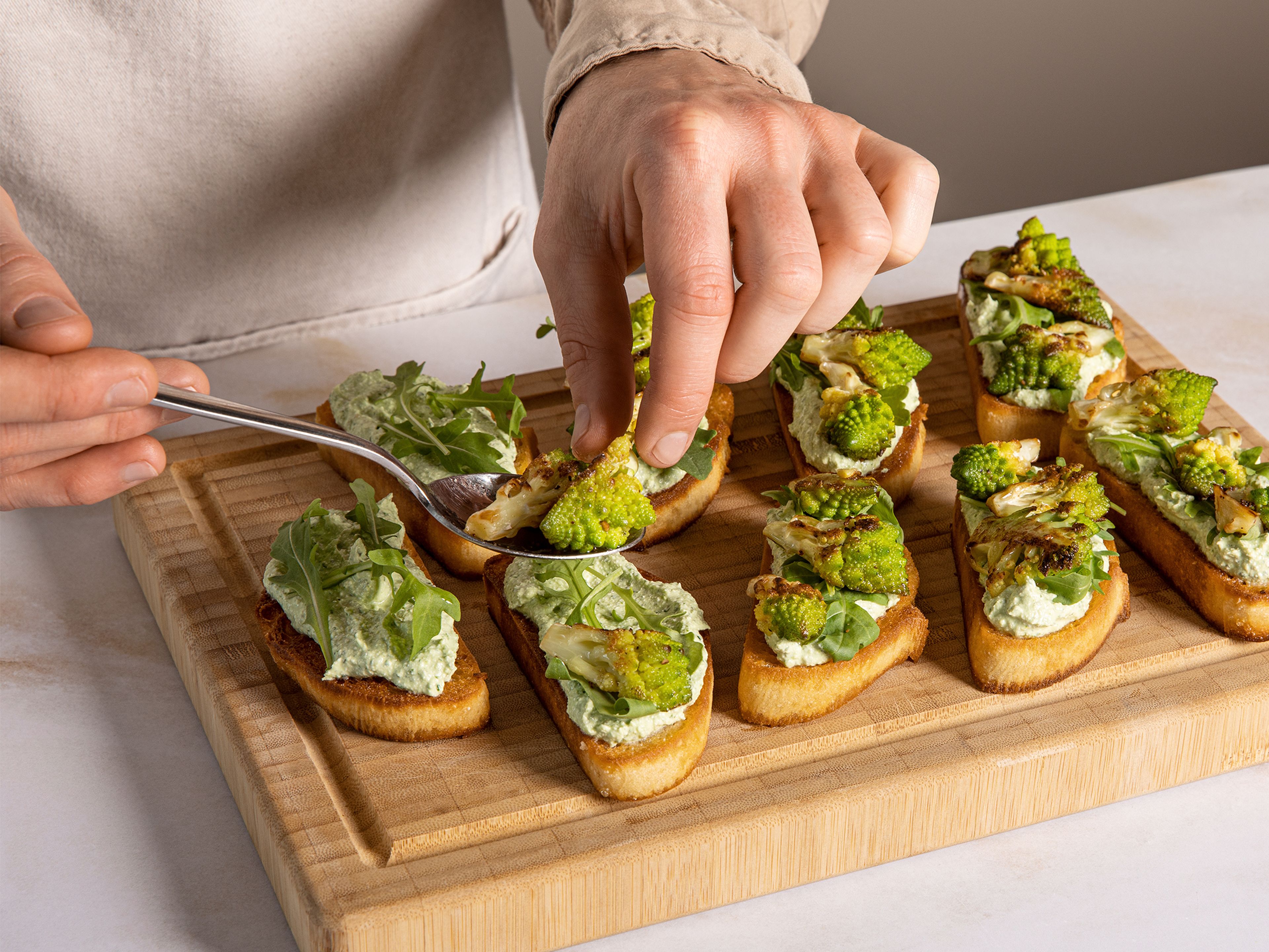 Spread the cottage cheese and basil cream on the toasted ciabatta slices, arrange a few Romanesco florets on top, and garnish with arugula, a little olive oil, sea salt, pepper, and lemon zest.
