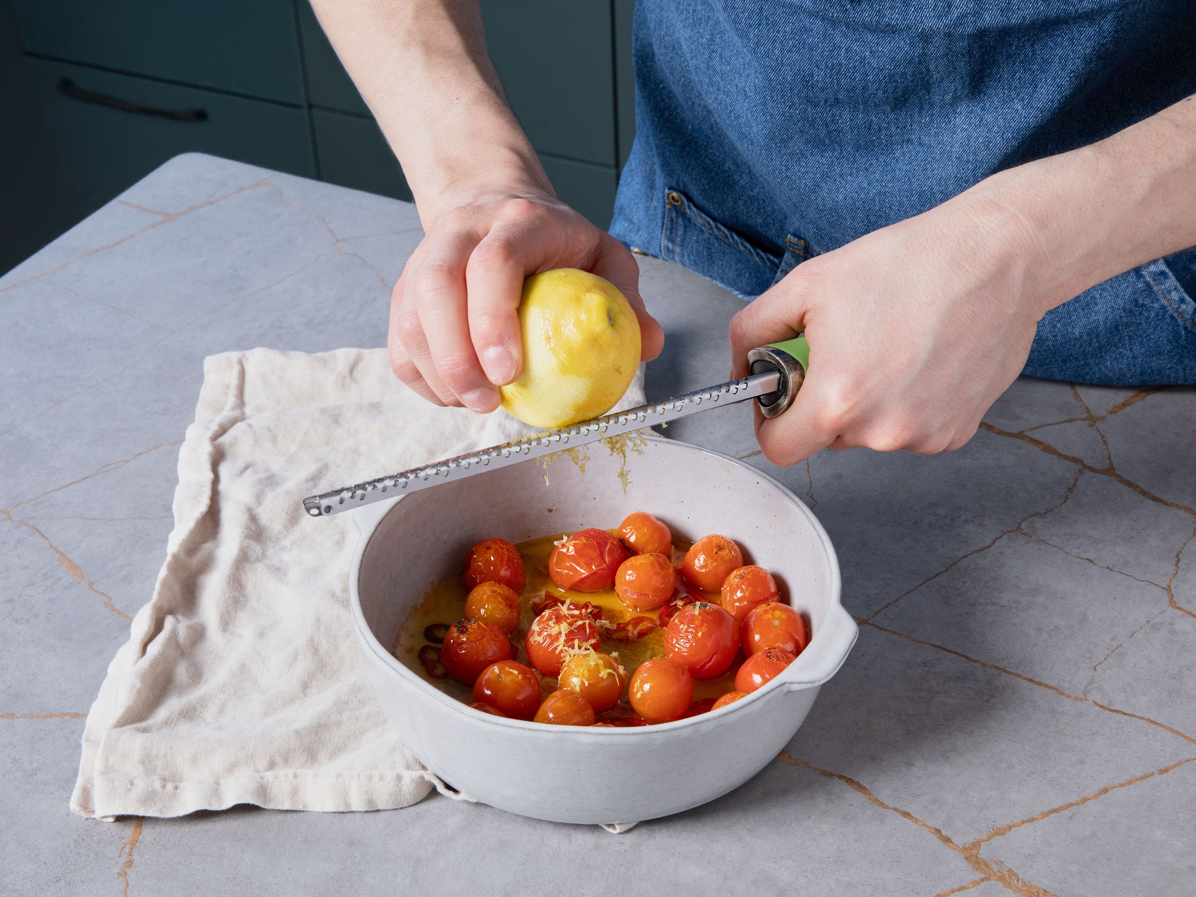 Spaghetti in reichlich gesalzenem Wasser nach Packungsanweisung al dente kochen. Beim Abgießen etwas Kochwasser auffangen. Die Zitrone heiß abwaschen, etwas Schale abreiben und den Saft auspressen. Die gegarten Tomaten aus dem Ofen nehmen, mit Zitronensaft und -abrieb verrühren.