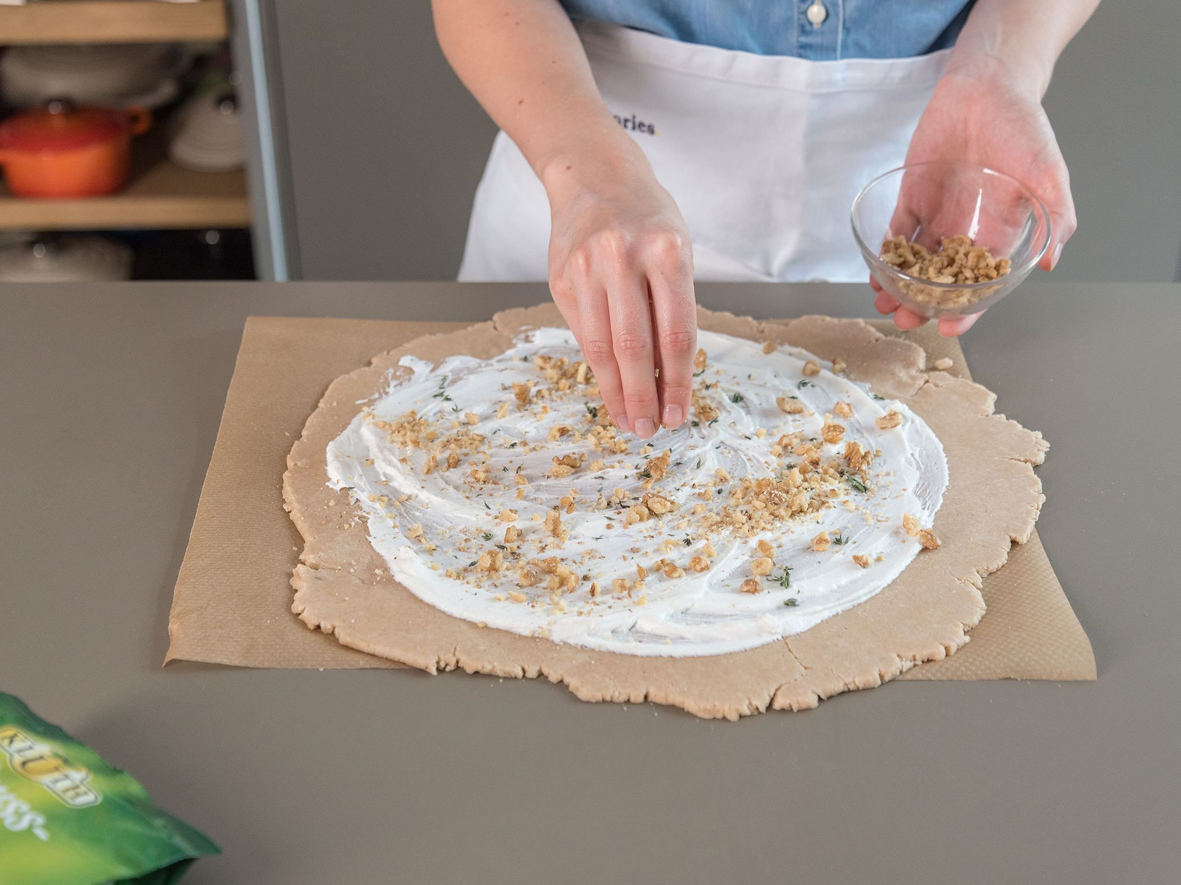 Remove dough from the fridge and set over a sheet of parchment paper. Roll out into a circle approx. 34 cm/13 in. in diameter. Spread the goat cheese over the dough, leaving approx. 4 cm/1.5 in. around the perimeter, then sprinkle with chopped walnuts.