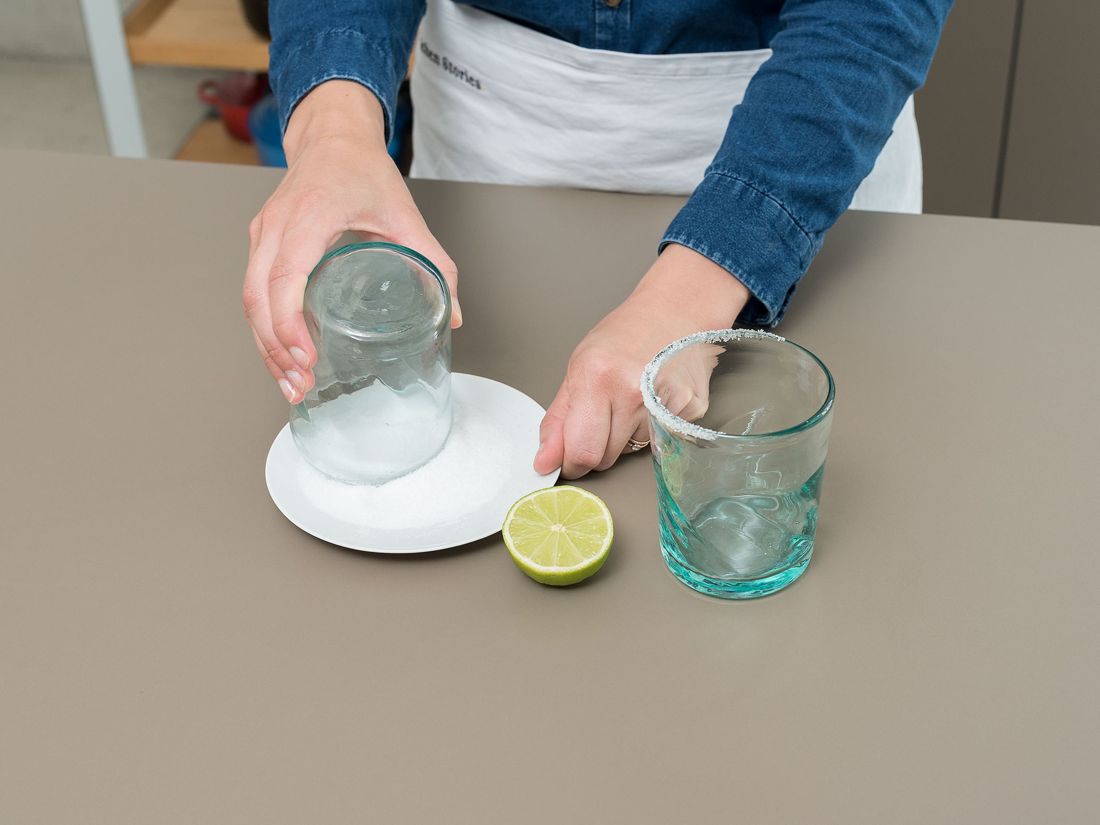Salz auf einen flachen Teller geben. Limette halbieren und damit um den oberen Glasrand fahren, um ihn zu befeuchten. Glasrand in Salz tunken. Gläser beiseitestellen.