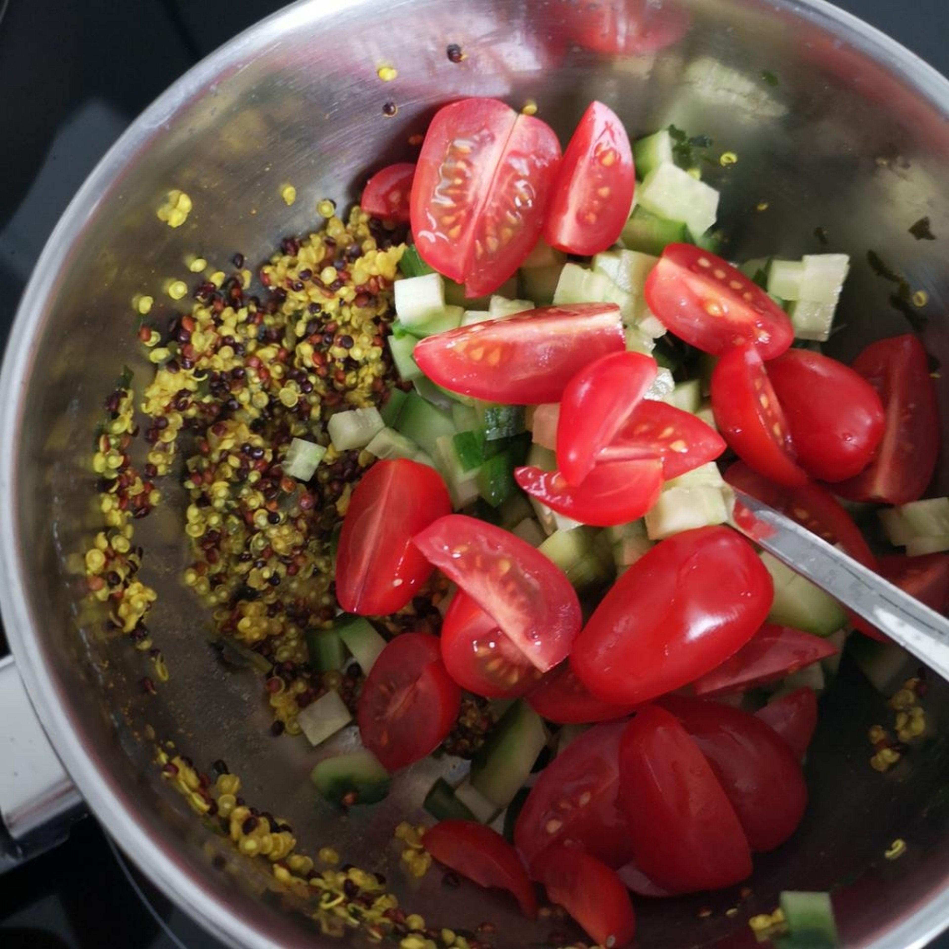 Geschnittene Gurke und Tomate in den Topf mit dem fertigen Quinoa geben und unterheben.