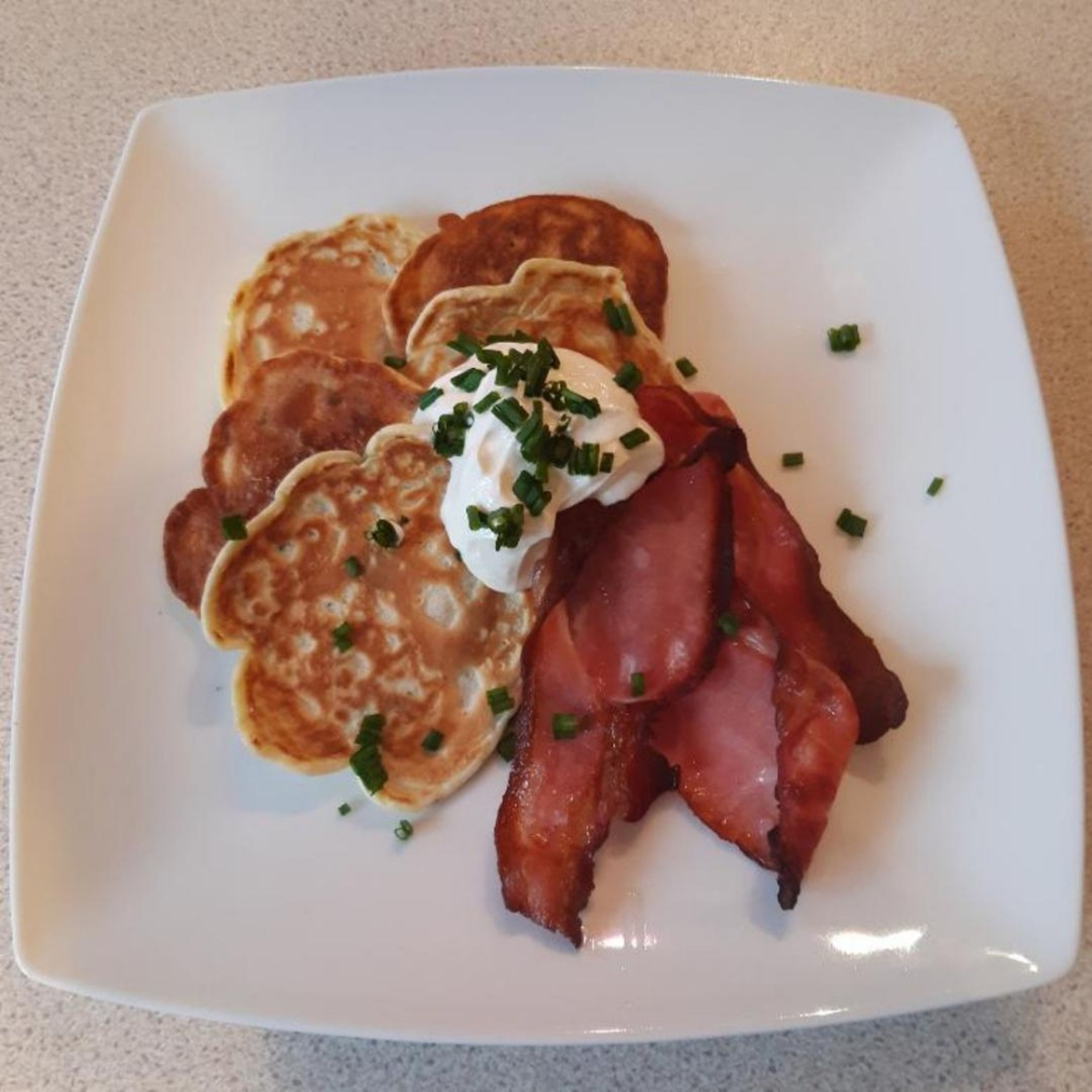 Assemble the pancakes and bacon on the plate and top with a tbsp of sour cream. Sprinkle the remaining chives over the top. Enjoy!