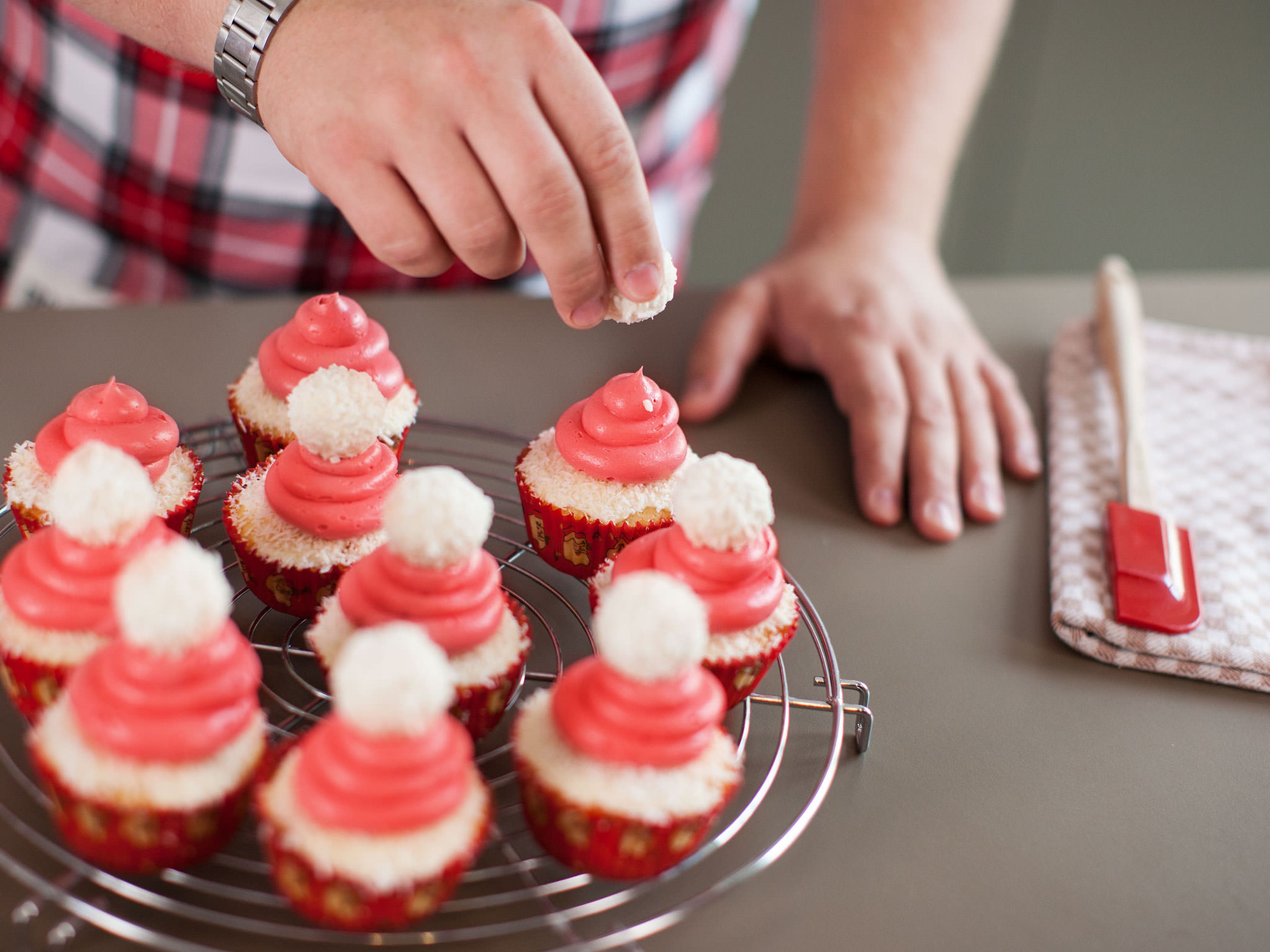 Mit der Crème auf jedem Cupcake eine kleine Nikolausmütze formen. Raffaellos darauf setzen.