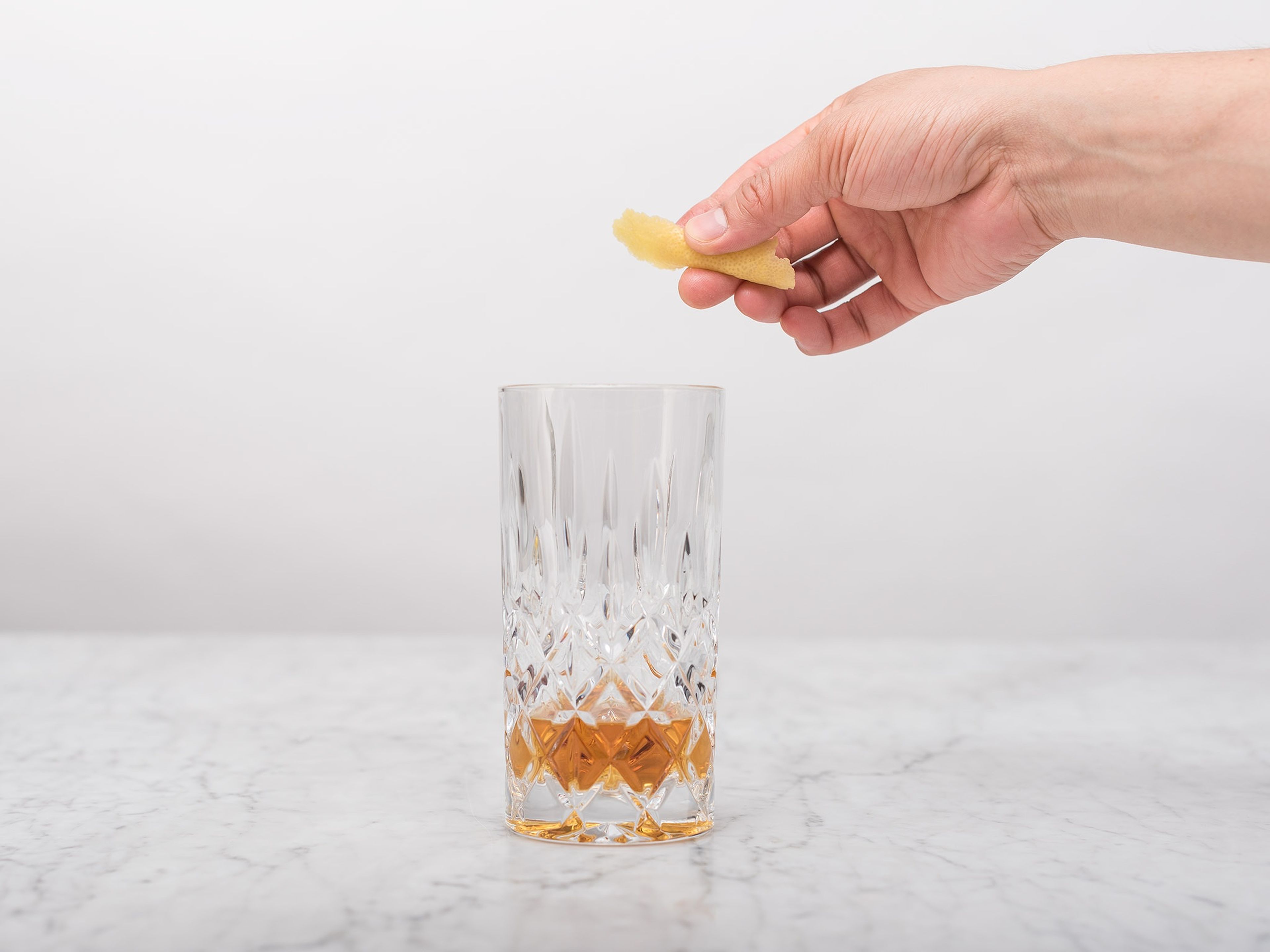 Für jedes Glas drei Zitronenschalen abschälen, spiralförmig in das Glas legen, wobei ein Ende über den Glasrand ragen sollte.