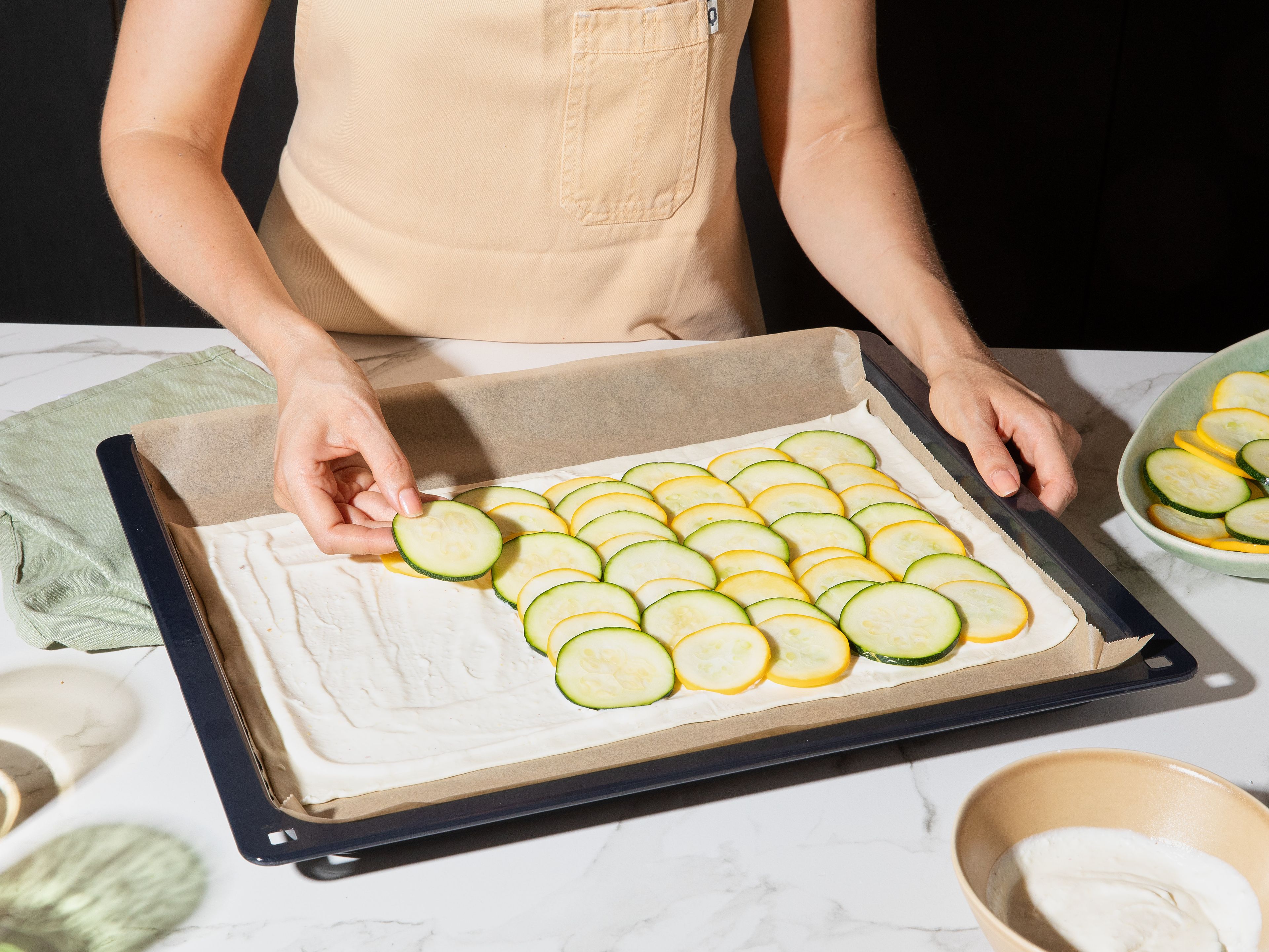 Roll out puff pastry on a baking sheet lined with parchment paper. Score a border approx. 2 cm wide around edge and prick the middle several times with a fork. Spread feta-crème-fraîche mixture evenly over pastry. Arrange zucchini slices on top in a slightly overlapping pattern and drizzle with olive oil. Bake the tart in the preheated oven for approx. 20 min. until puff pastry is golden brown and crispy.