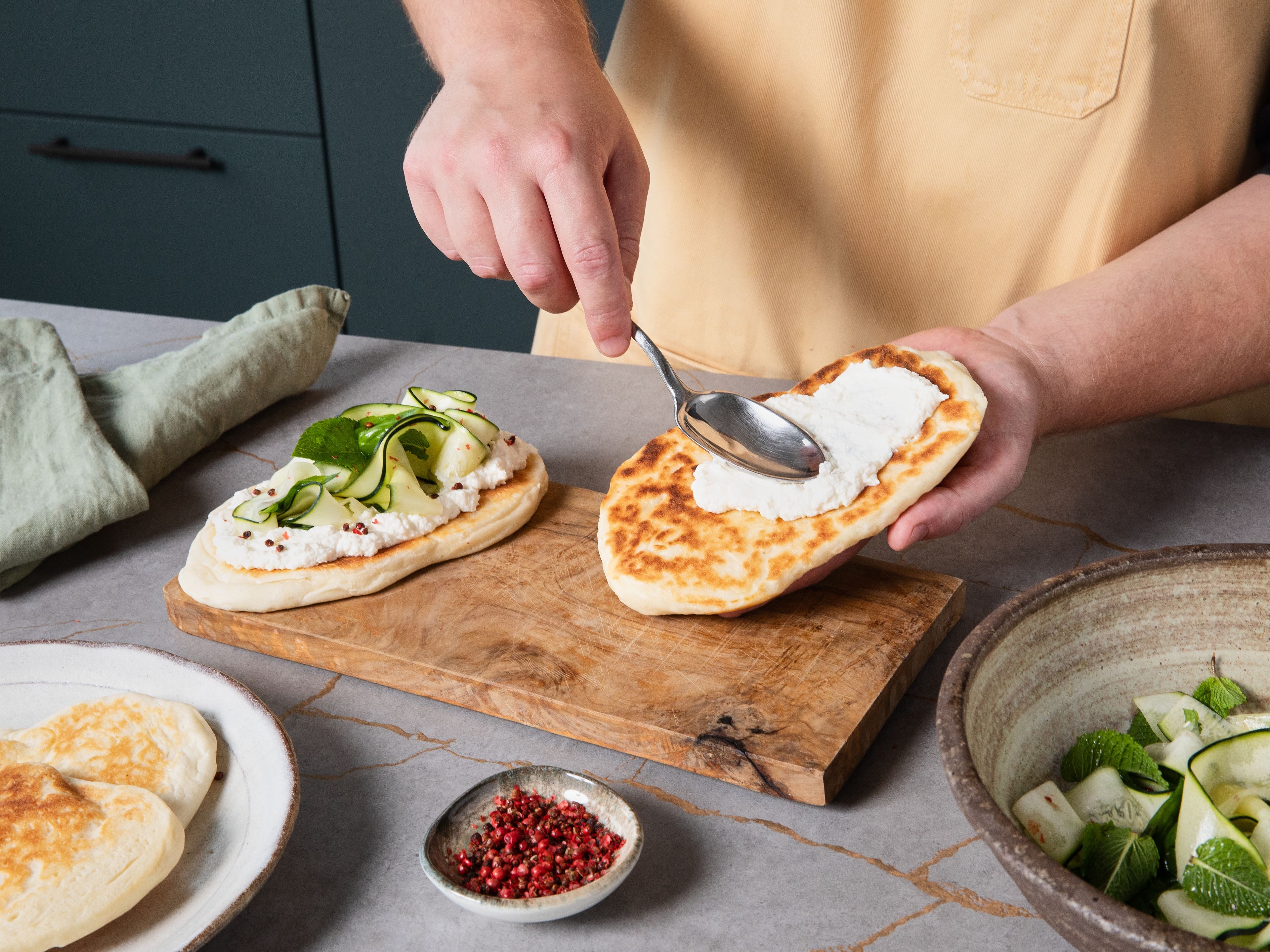 Parmesan fein reiben. Zusammen mit Ricotta und Olivenöl in eine Schüssel geben und gut durchmischen. Den Ricotta auf den Pfannenbroten verstreichen und mit den marinierten Zucchinistreifen toppen. Mandelblättchen in der Pfanne goldbraun anrösten und auf die Pfannenbrote streuen.