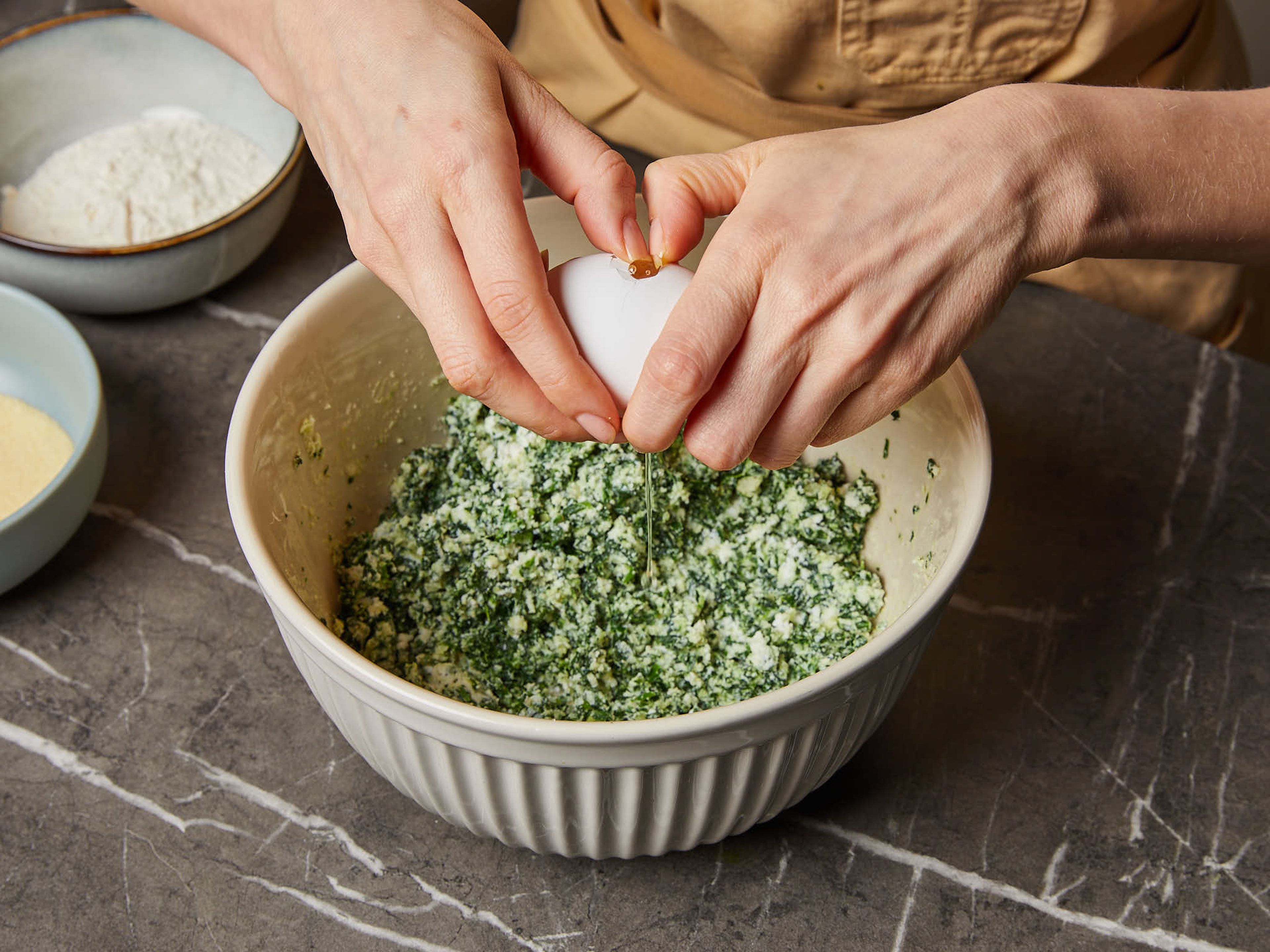 To a mixing bowl, add the wild garlic mix, parmesan and strained ricotta, then stir to combine and work in the egg. Season well with salt, pepper and nutmeg. Gradually mix in the flour and semolina until you have a uniform dough, without overmixing it.