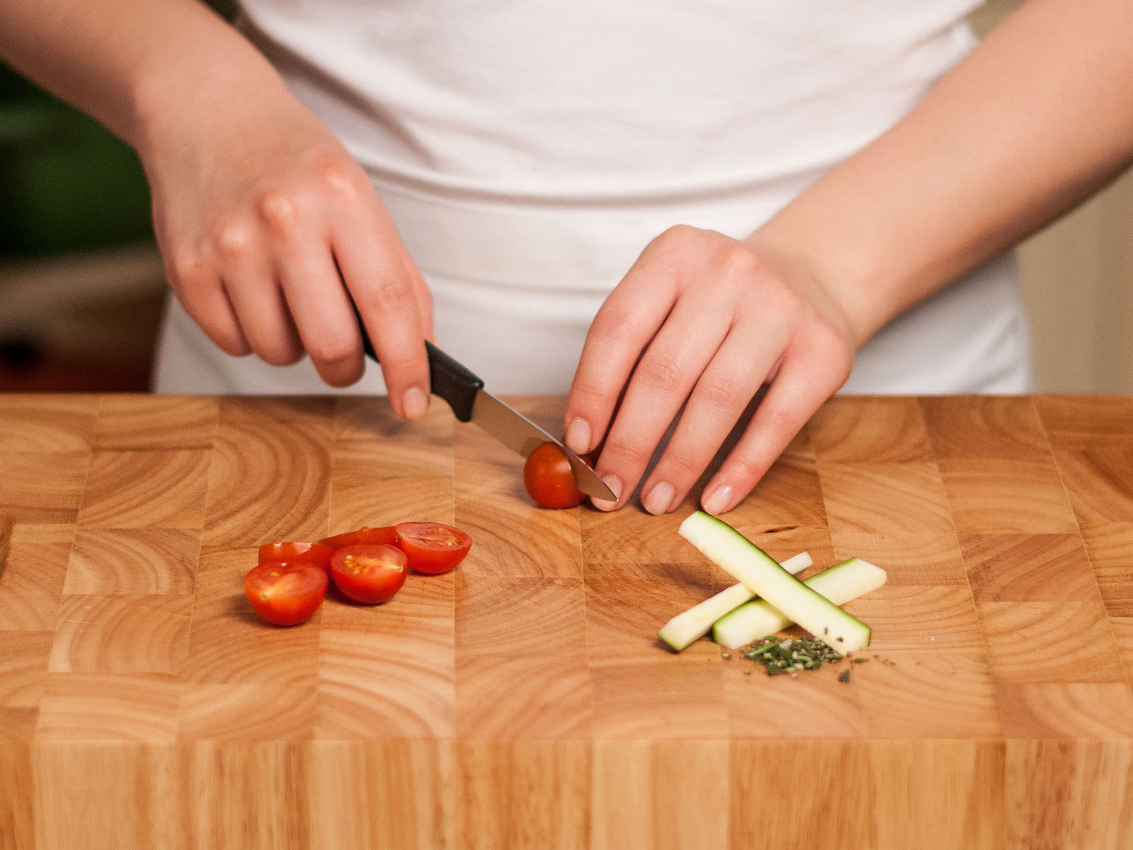 Zucchini halbieren und in Sticks schneiden. Rosmarin fein hacken und Tomaten halbieren.