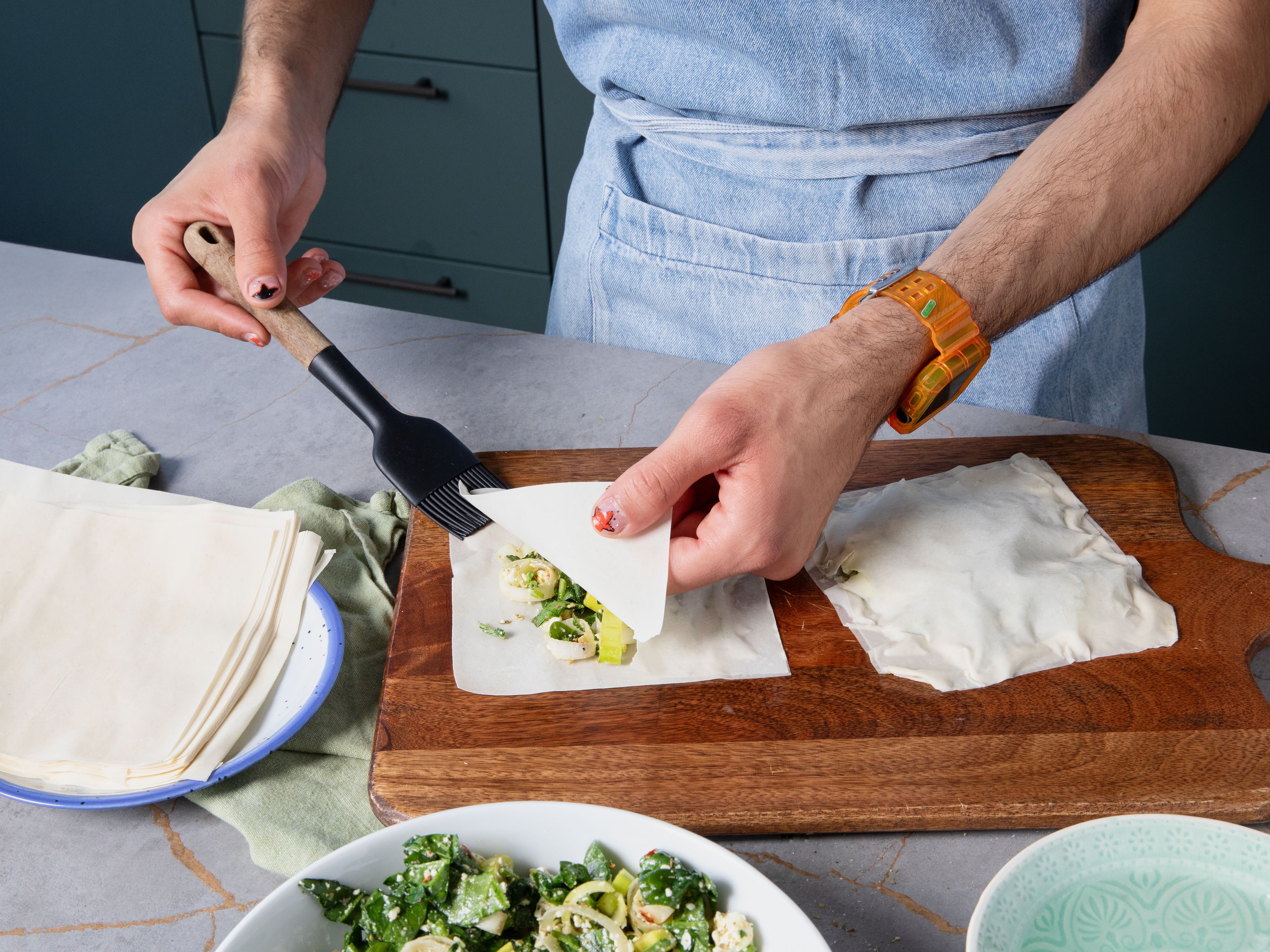 Spread phyllo dough and cut into equal square pieces. Place two squares on top of each other, and put approx. 1,5 tbsp of filling and spread. Fill a small bowl with water. Place two more squares on top, and brush every side with water until they stick to each other.