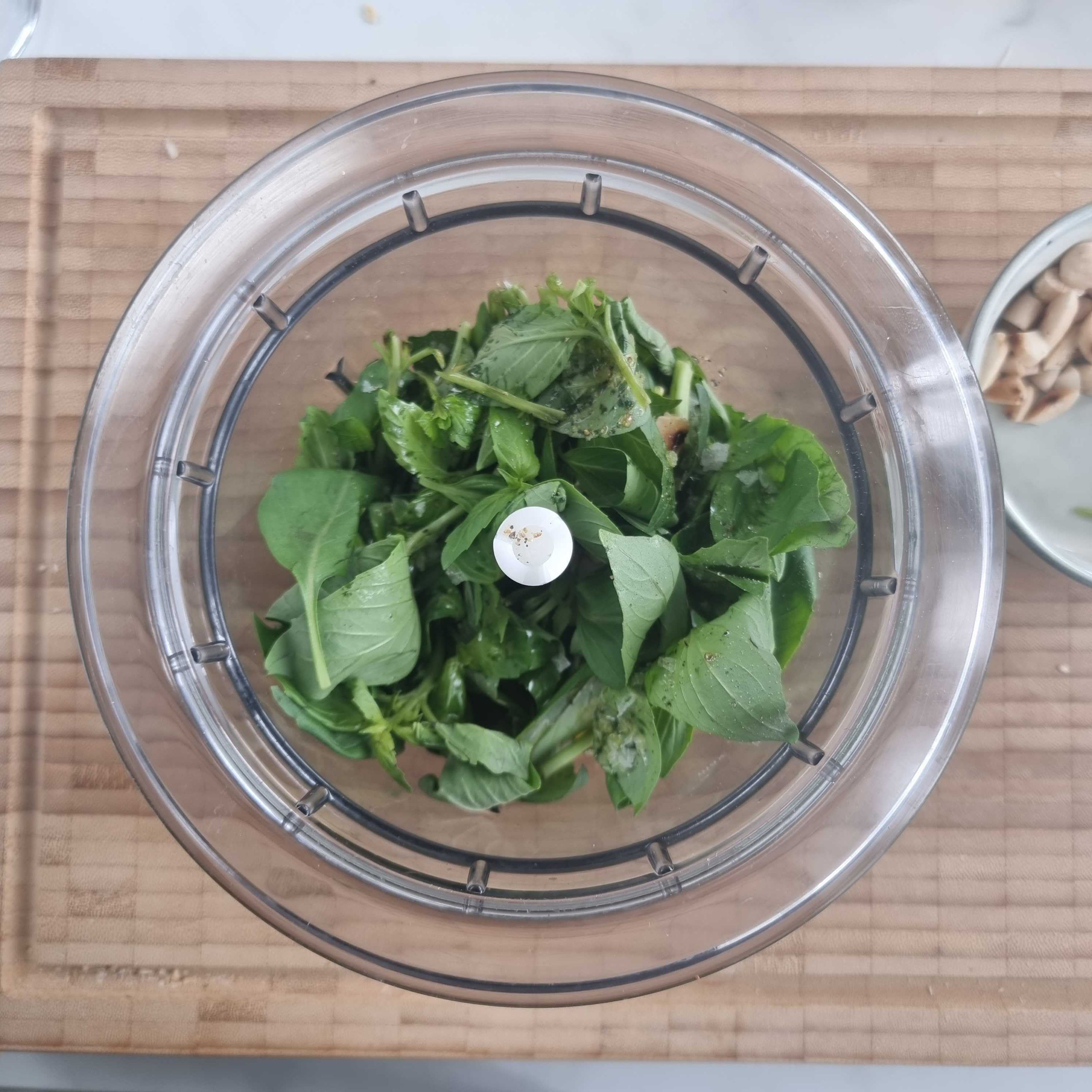 Add half of the almonds, basil, salt, pepper, lemon zest and the remaining olive oil to a food processor and process until smooth. Transfer the pesto to a large bowl.