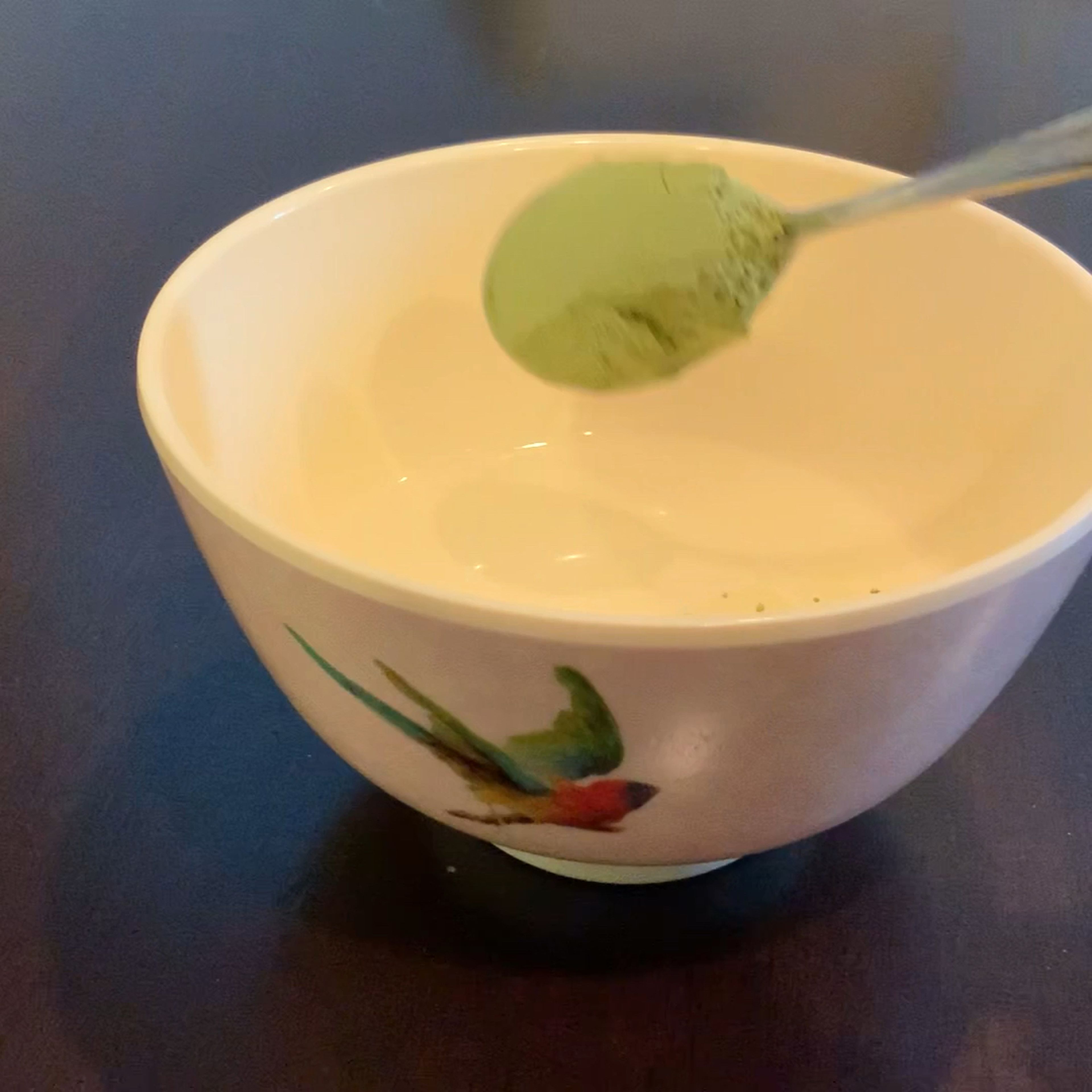 Mix hot water with matcha powder in a small bowl, with a spoon.