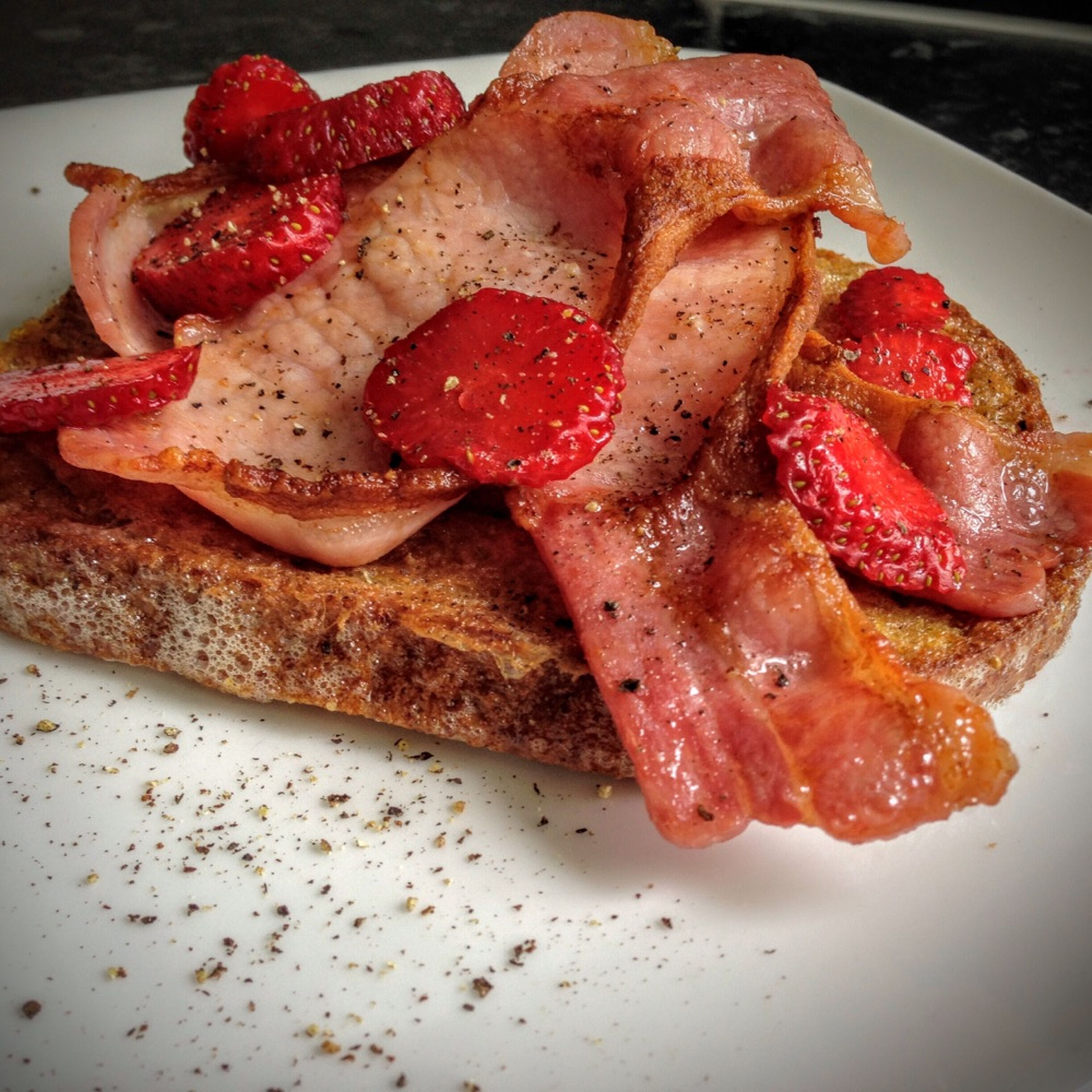 Fry the bread in a little butter until golden brown. Serve with bacon, strawberries, and a little black pepper. Enjoy!