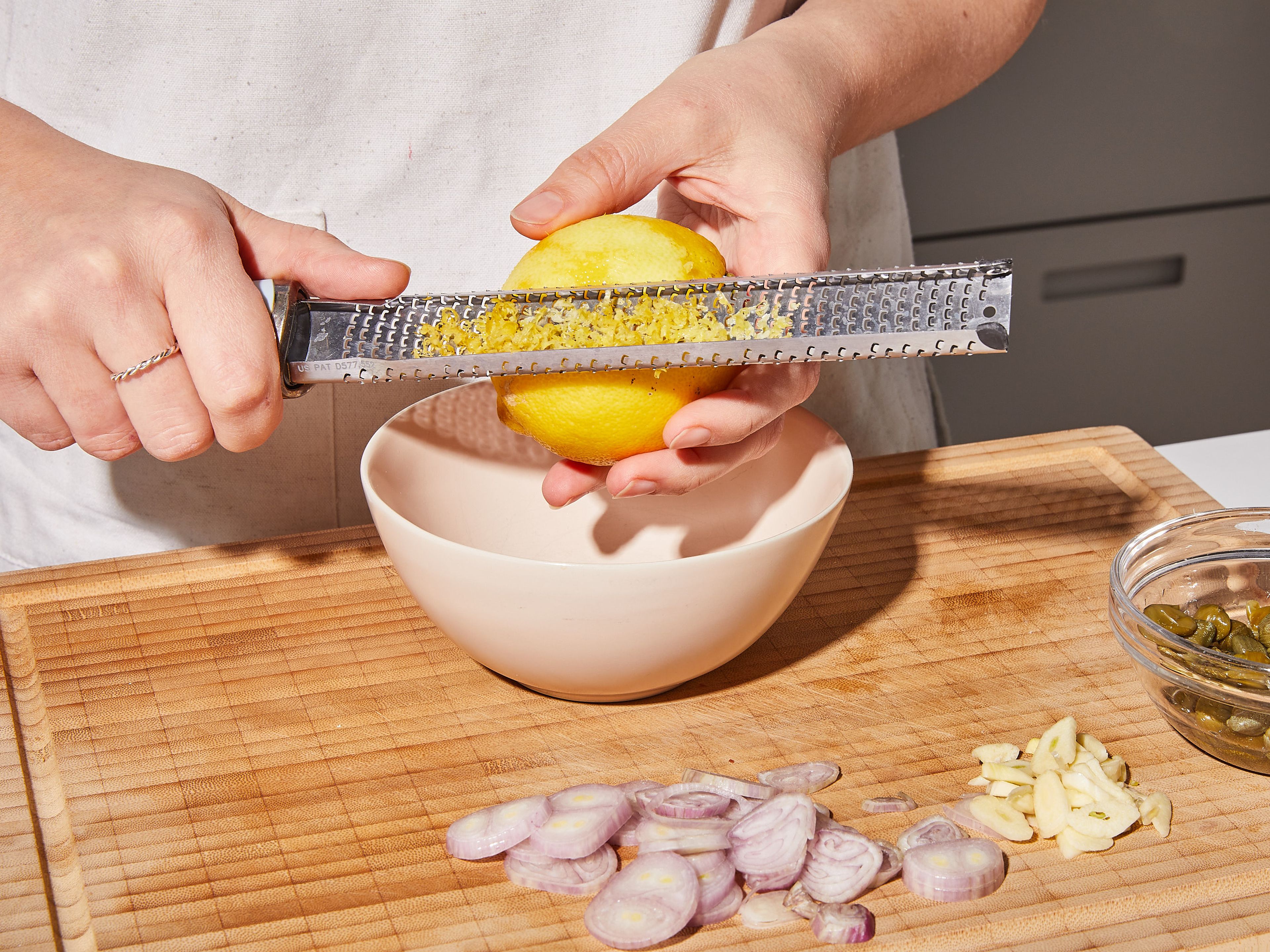 Knoblauch und Schalotte schälen und in feine Scheiben schneiden. Zitronenschale abreiben, dann die Zitrone halbieren. Eine Hälfte auspressen und den Saft in eine kleine Schüssel geben. Die andere Hälfte in Stücke schneiden und bis zum Servieren zur Seite stellen.