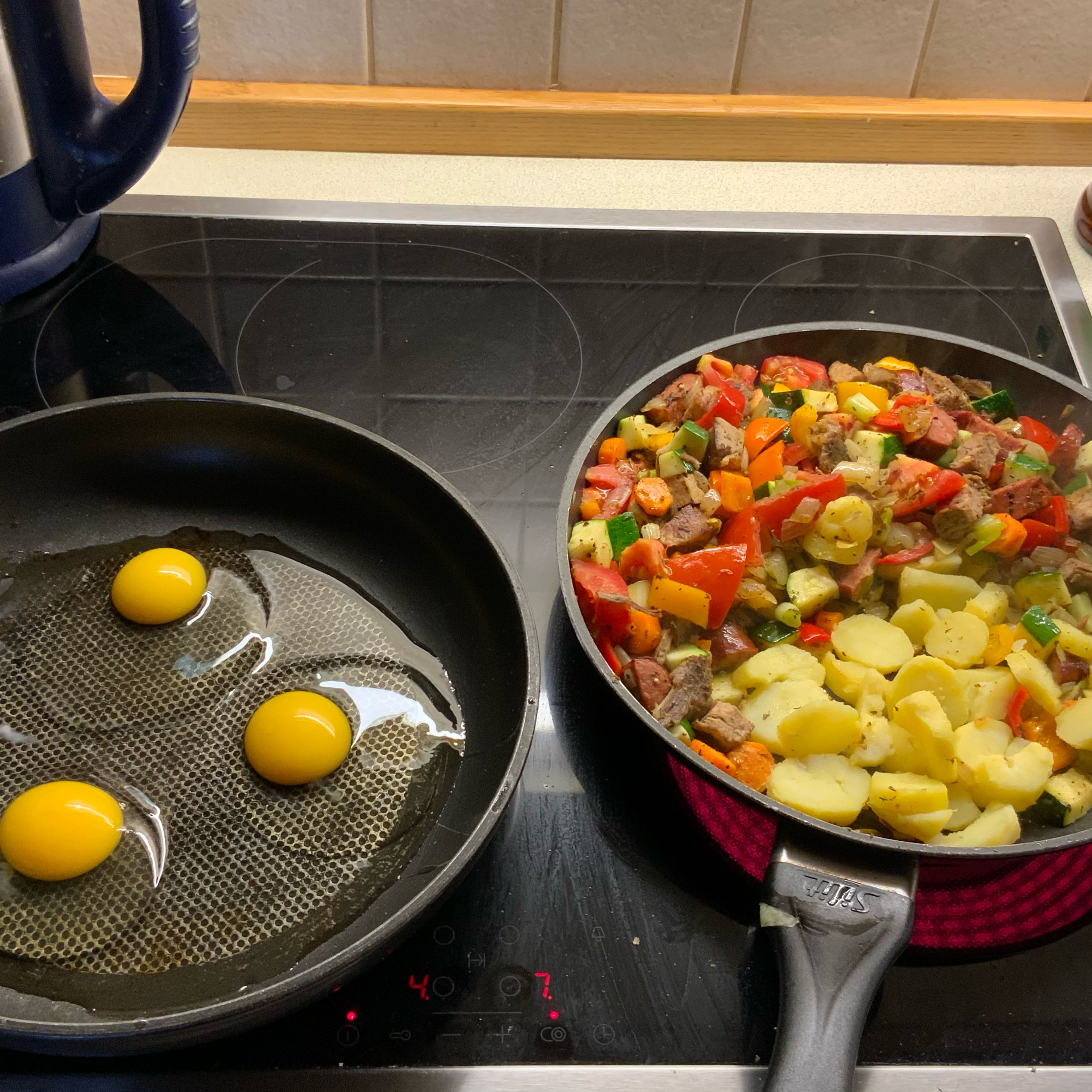 Die Bratkartoffeln in der einen Pfannenhälfte kross anbraten, das Gemüse falls in einer getrennten Pfanne gemacht nicht mehr weiter braten, es soll knackig bleiben. In einer zweiten Pfanne drei Eier als Spiegeleier aufschlagen.