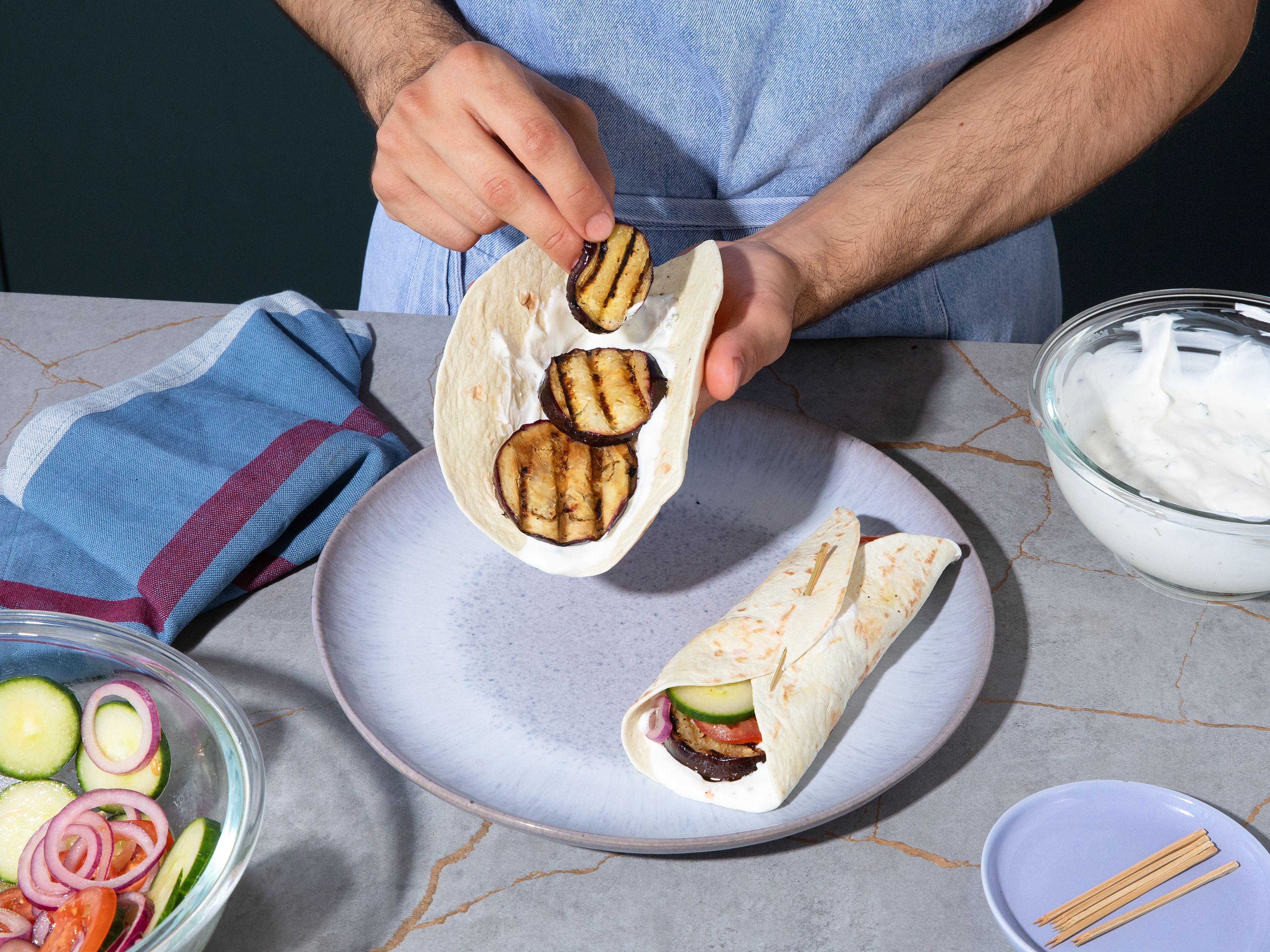 Die Tortillas mit der Joghurtsoße bestreichen. Gegrillte Auberginen und den Salat darauf verteilen. Petersilie grob hacken und darüberstreuen. Nach Belieben noch etwas Zitronensaft darübergeben, die Tortillas fest aufrollen und sofort servieren.
