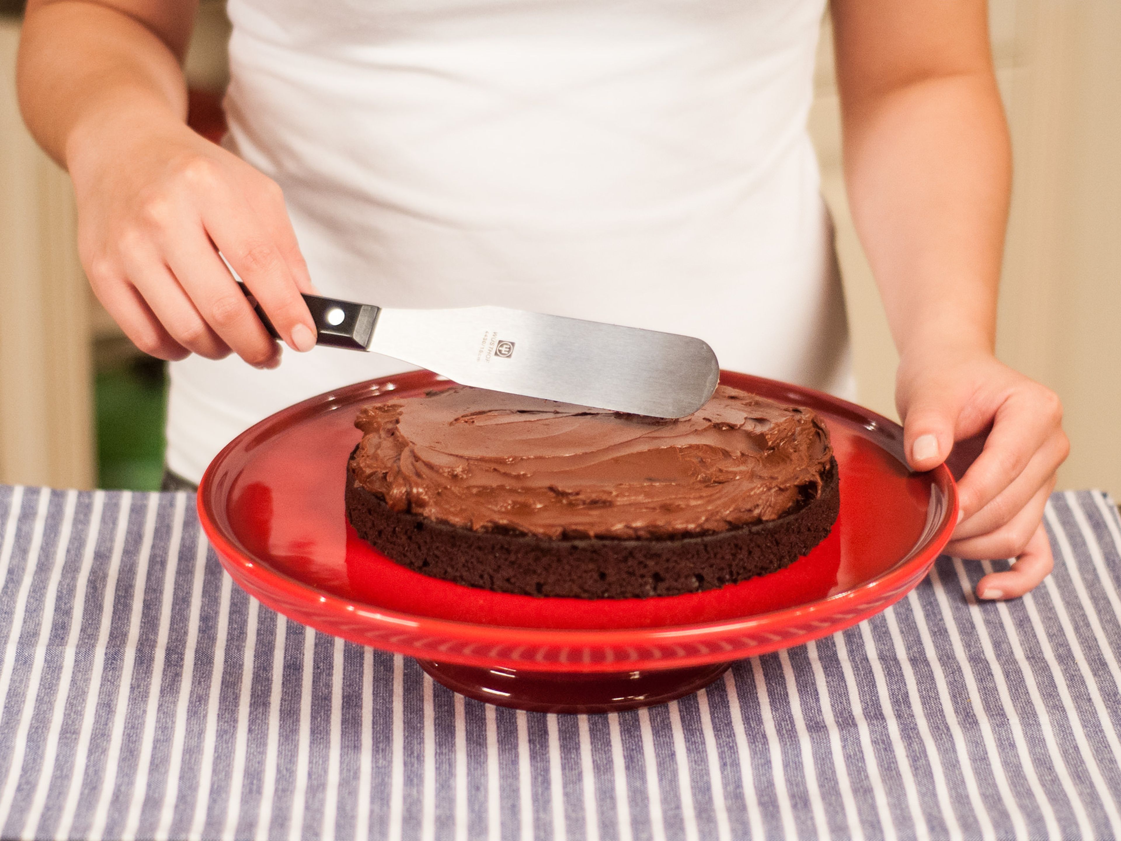 Release the cake and spread a generous amount of the chocolate mixture onto the first cake base.