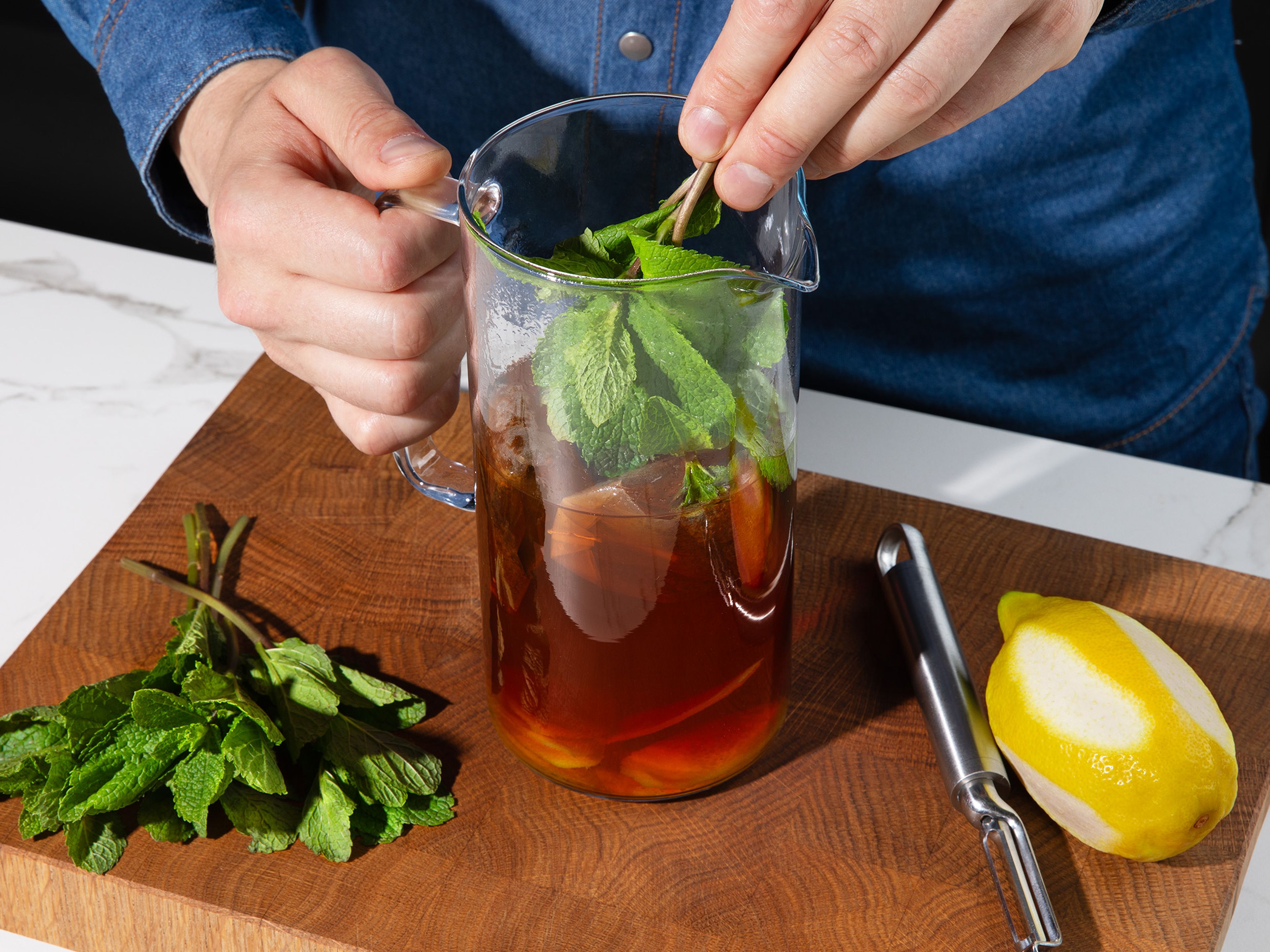 In the meantime, boil water in a kettle or on the stove. Place tea bags, sprigs of mint, and lemon peels in a jug and pour the boiling water over. Let sit for approx. 5 min. Remove tea bags, lemon peels, and mint. Allow to cool slightly.