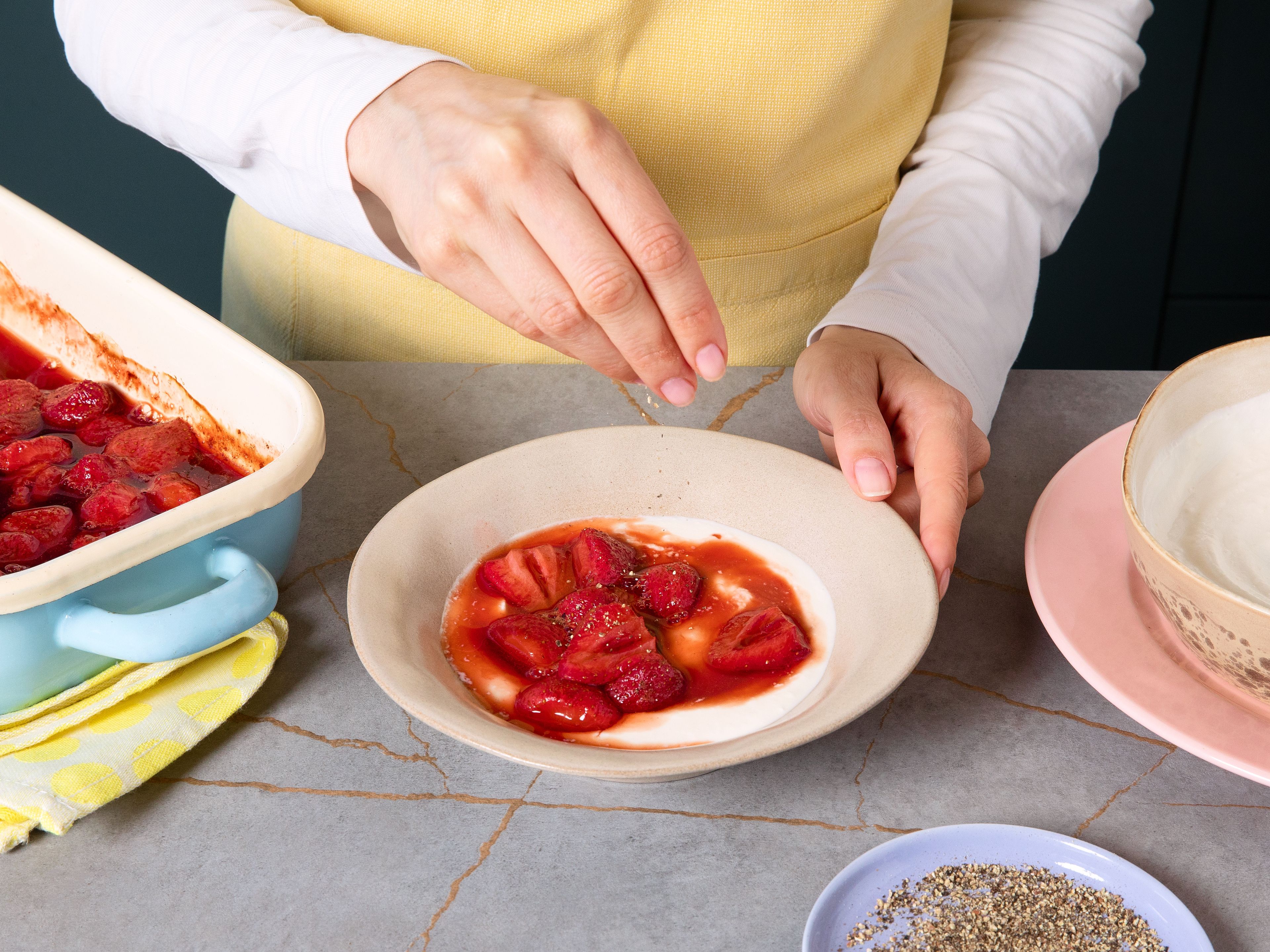 Remove strawberries from oven and let cool. Place ricotta cream in bowls. Distribute lukewarm strawberries with some of their juice on top. Finish bowls off with freshly ground black pepper, and optionally lemon zest on top. Serve immediately.