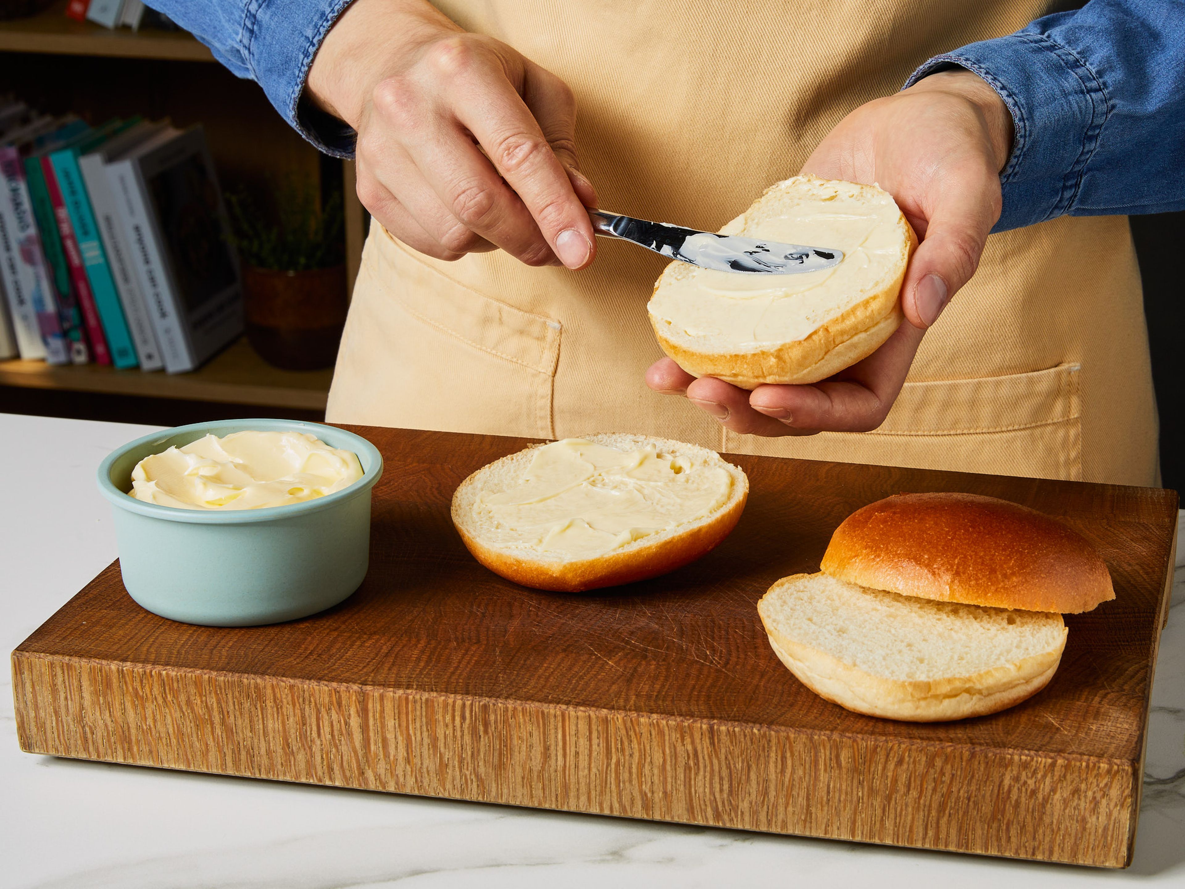 Grill oder Grillpfanne vorheizen. Burgerbrötchen halbieren und mit Butter bestreichen. Anschließend auf beiden Seiten für ca. 1–2 Min. auf den Grill oder die Grillpfanne legen. Dann beiseitelegen.