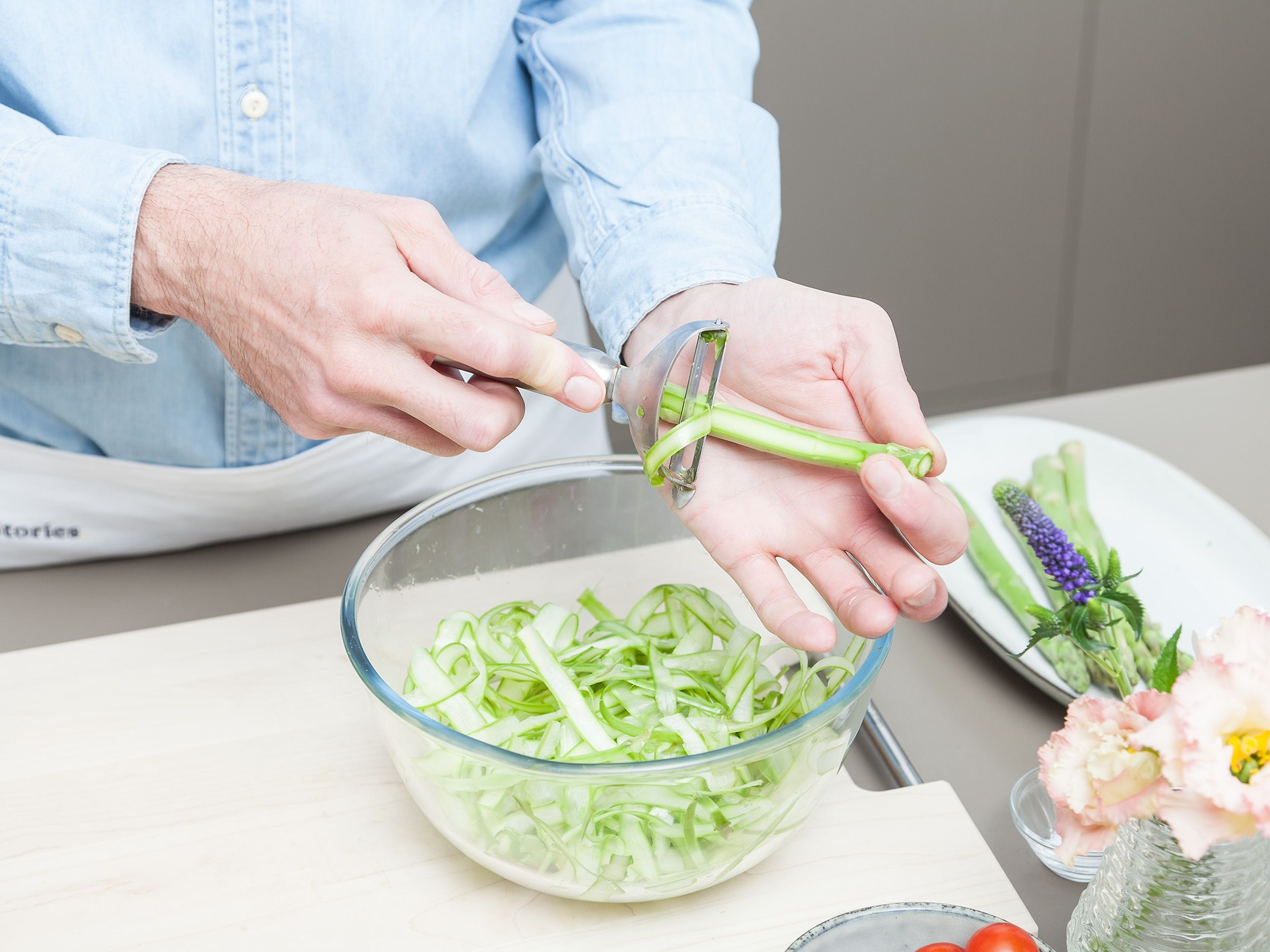 Remove and discard the woody bottom ends of the asparagus. Cut off asparagus heads and add to a large bowl. Shave asparagus stems, quarter tomatoes, and add both to the bowl. Sprinkle with sugar and salt and mix to combine. Let sit for approx. 5 min.