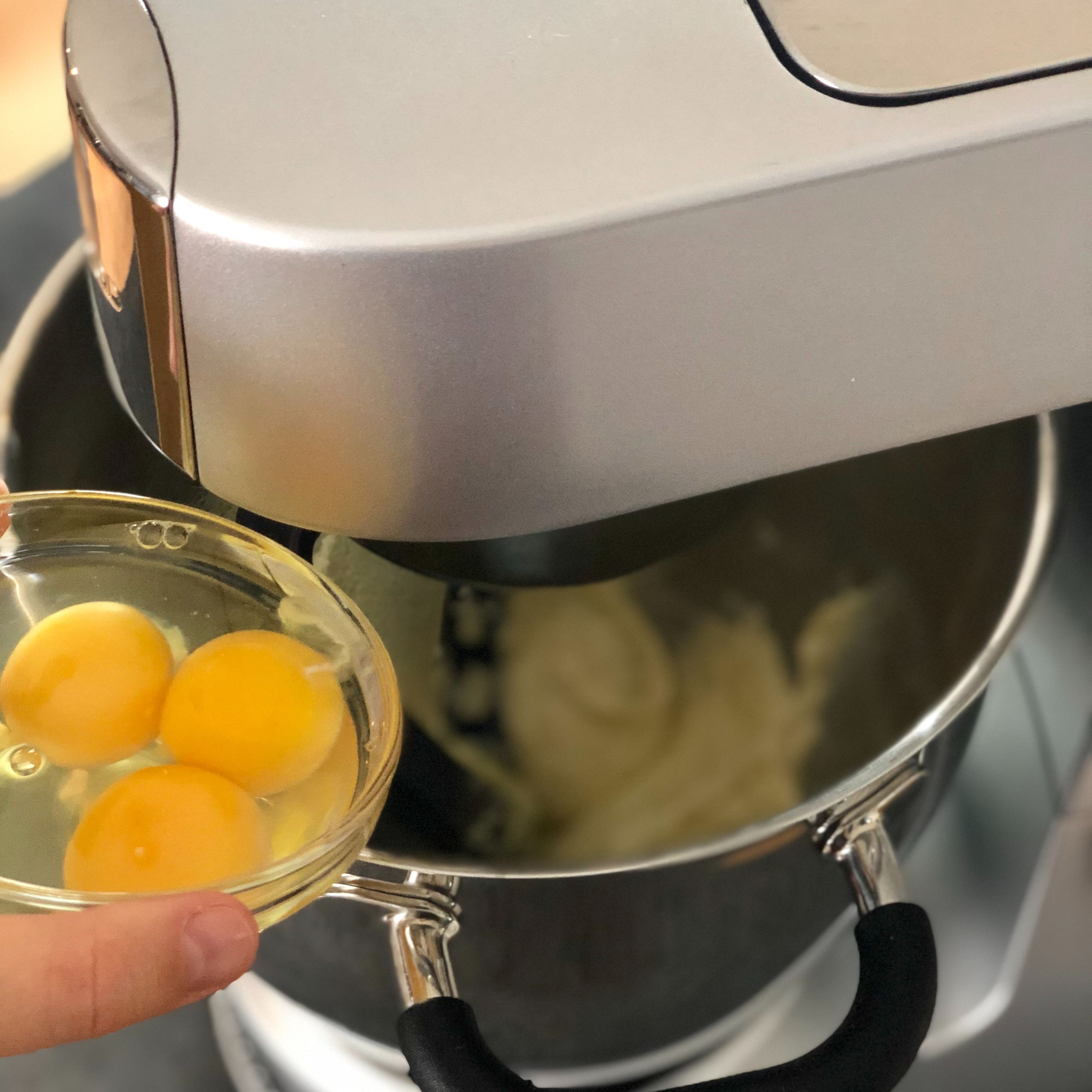 Nach und nach die Eier, Zitronensaft und -schale dazu geben.