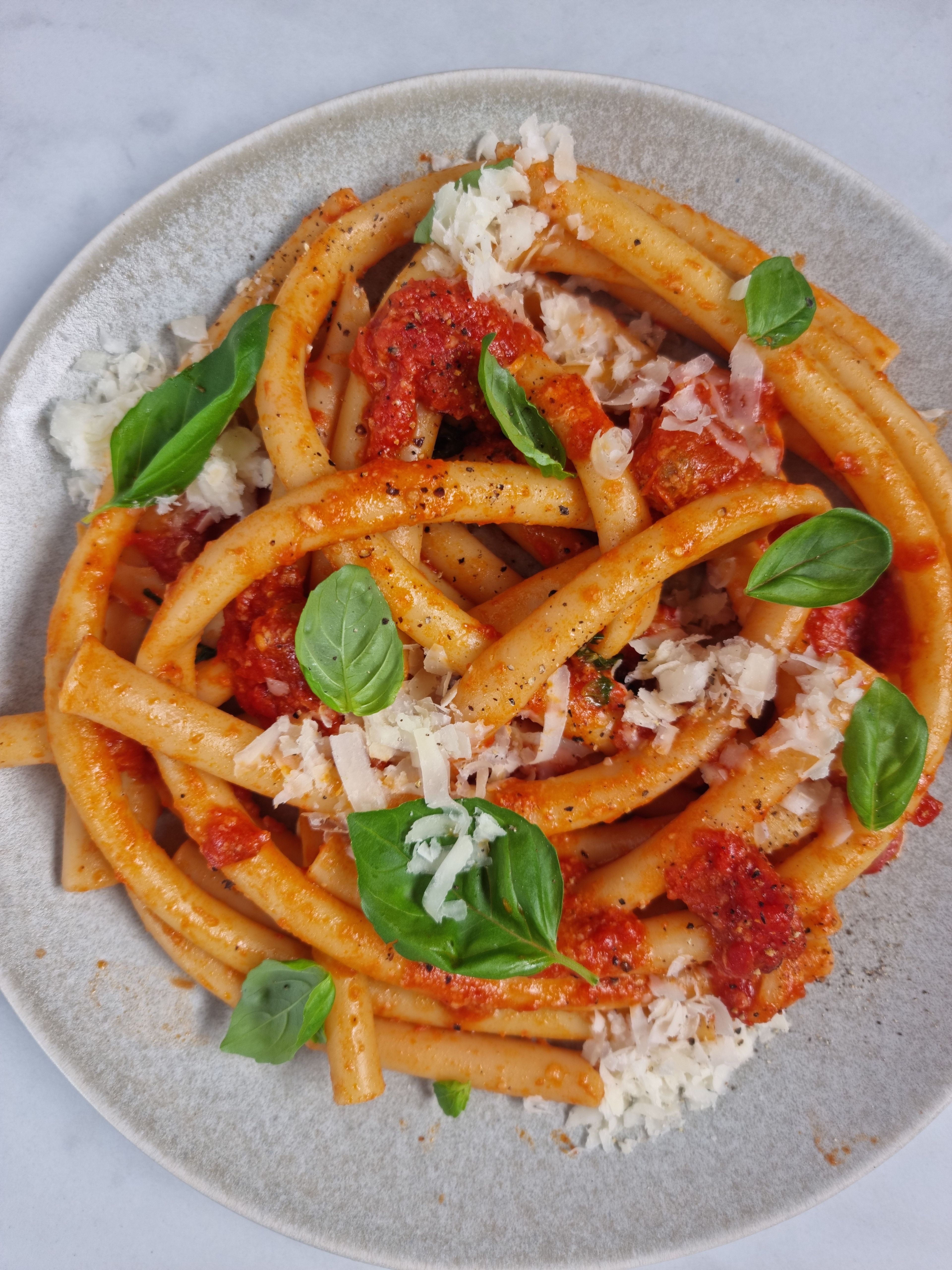 Season the sauce with salt and pepper. Drain the pasta and combine with the sauce in the pan. Stir half of the Parmesan cheese into the pasta. Plate and garnish with remaining Parmesan and more basil. Enjoy!