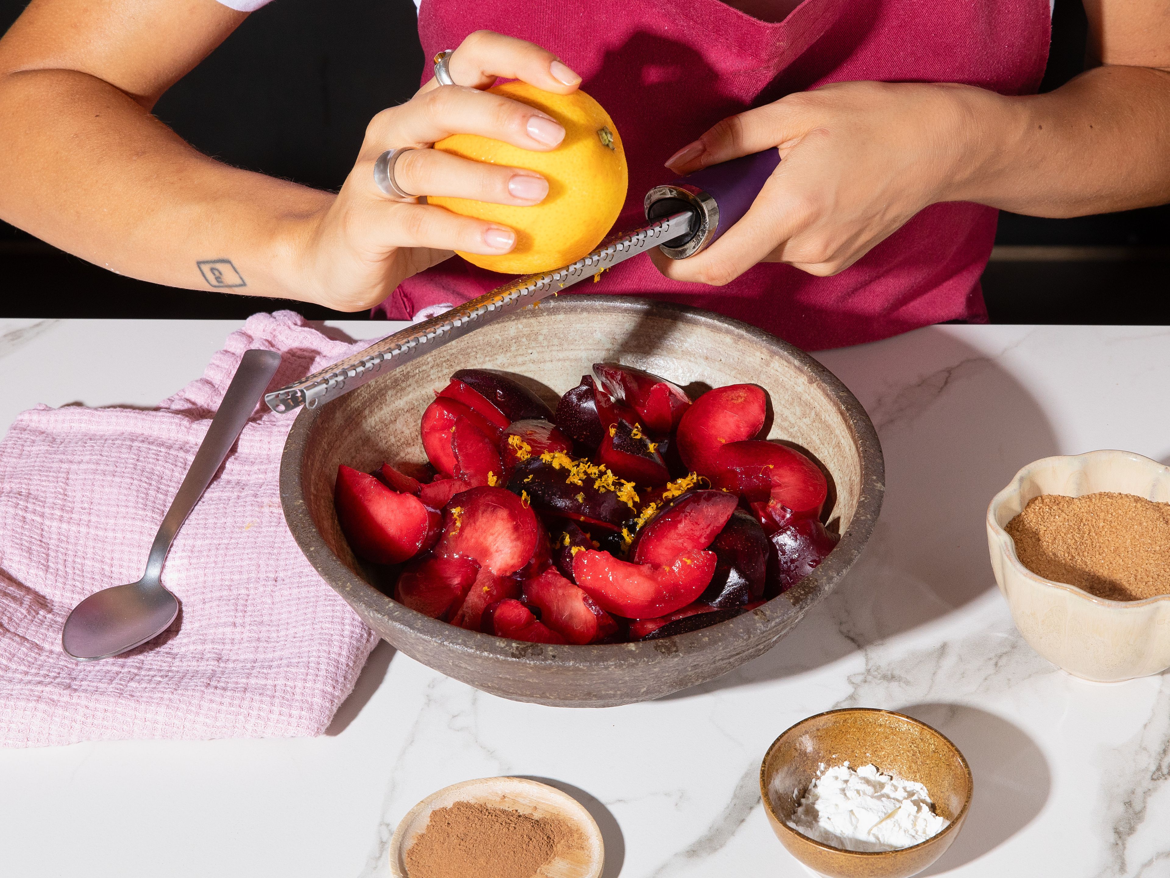 Preheat oven to 190°C/375°F. Grease an oven proof skillet (approx. 25 cm/10 in.) with butter. Set aside 1 tbsp of the brown sugar. Zest the orange, juice the lemon and cut plums into wedges. Toss the plums with the remaining brown sugar, cornstarch, cinnamon, lemon juice, and orange zest, then transfer to the prepared skillet.
